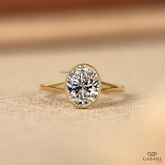 Oval cut lab grown diamond bezel set ring in yellow gold