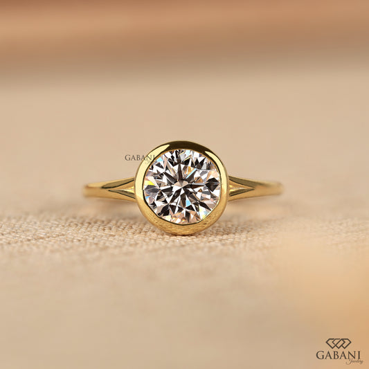 Bezel set round lab grown diamond solitaire ring in yellow gold with split shank design