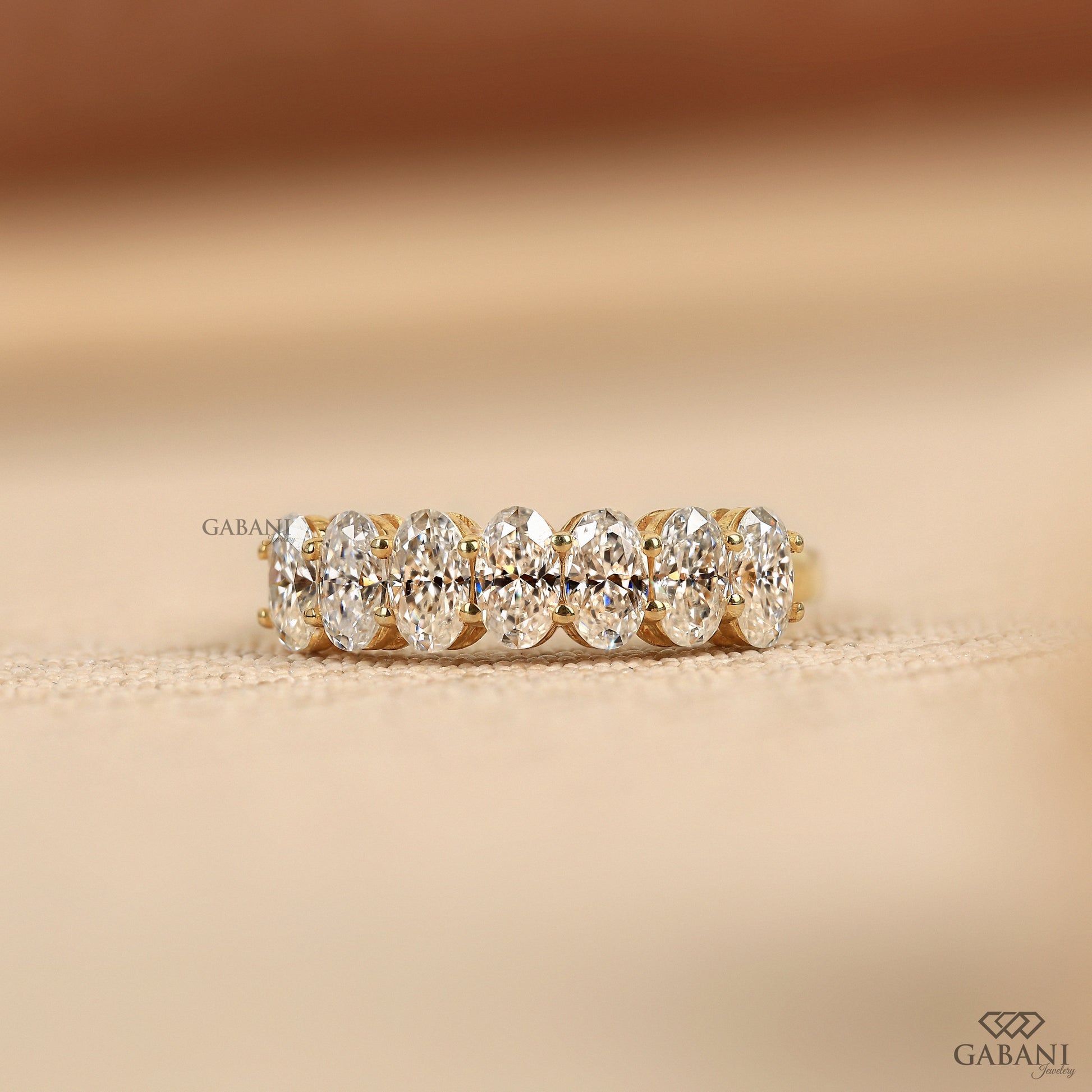 seven stone lab grown diamond band in 14k yellow gold with oval diamonds and half eternity design