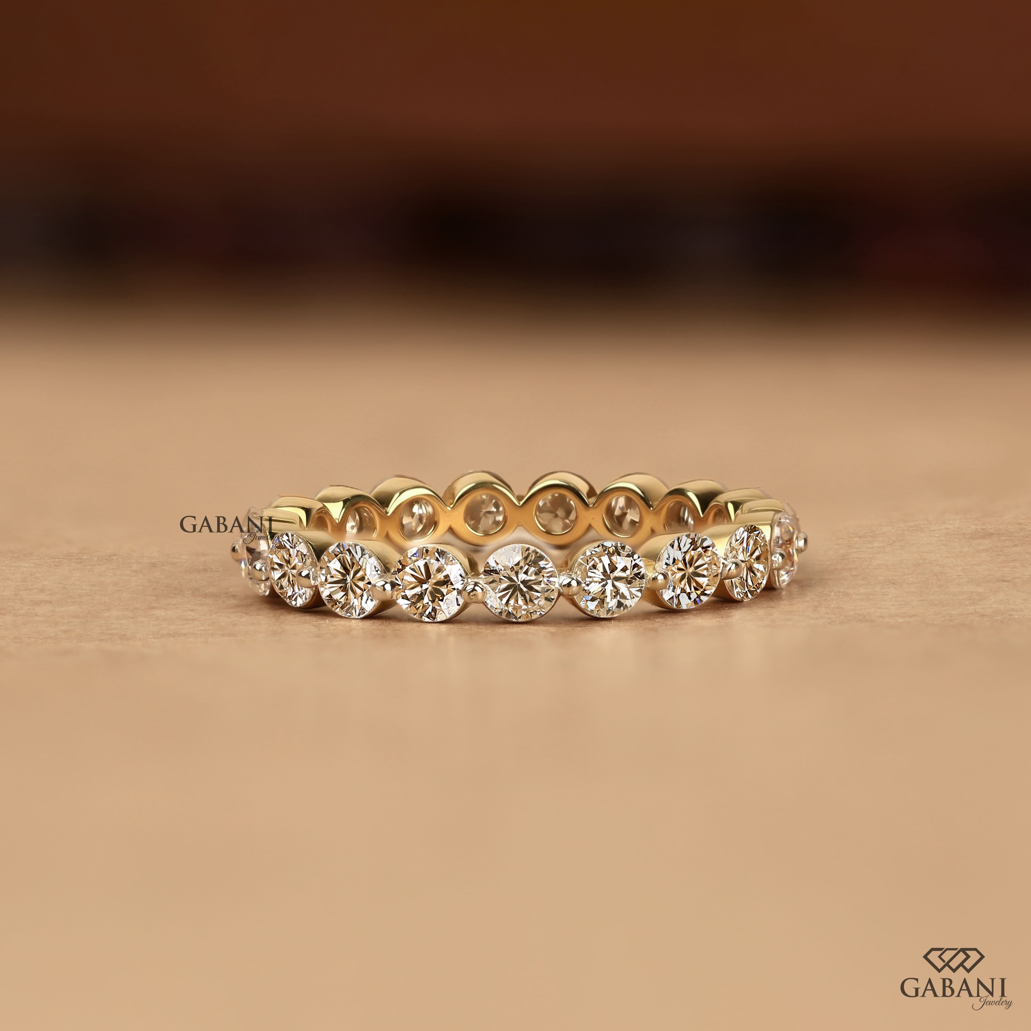 Round cut lab grown diamond full eternity wedding band in yellow gold with shared prong setting.