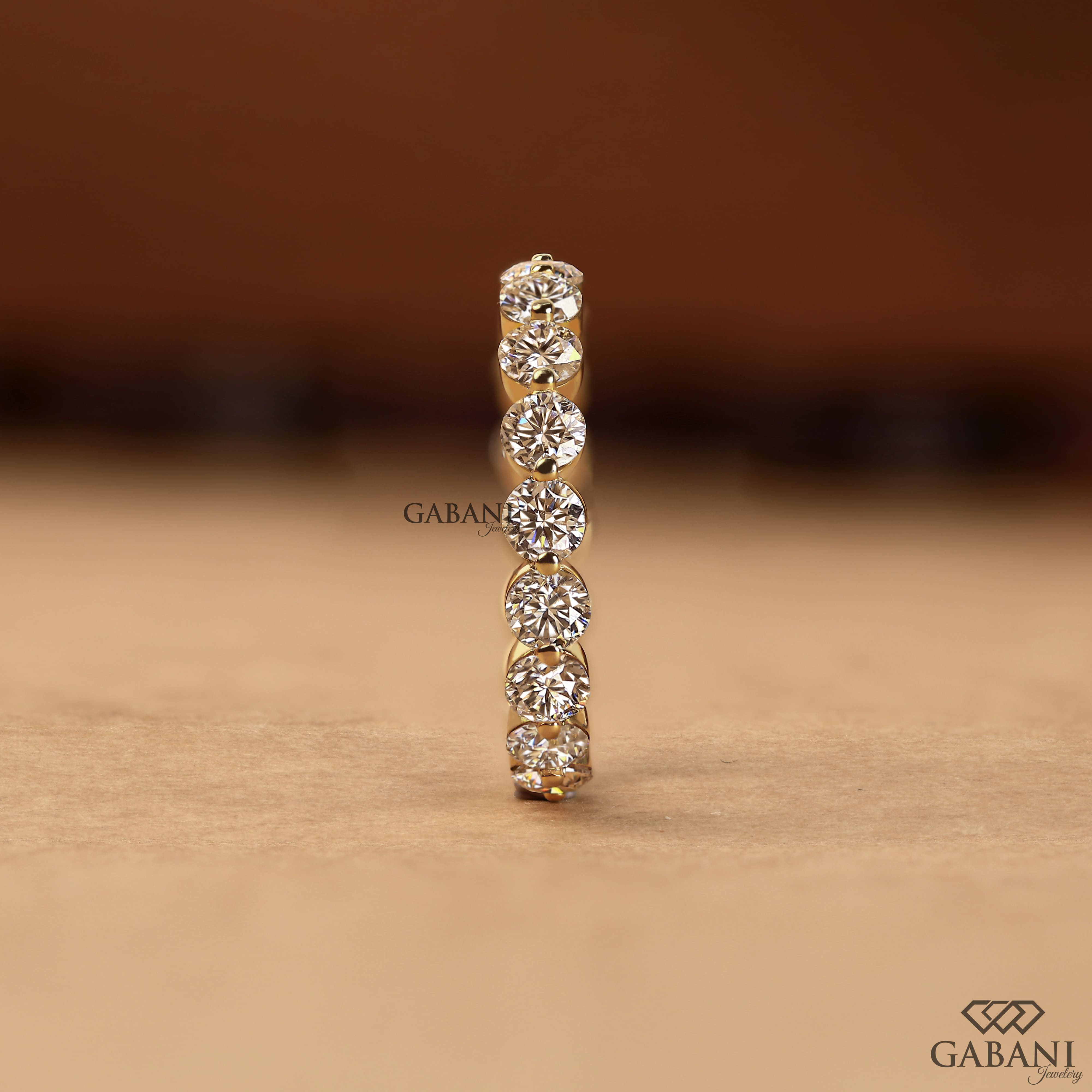 Round lab grown diamond shared prong full eternity wedding band in yellow gold with continuous diamond setting.