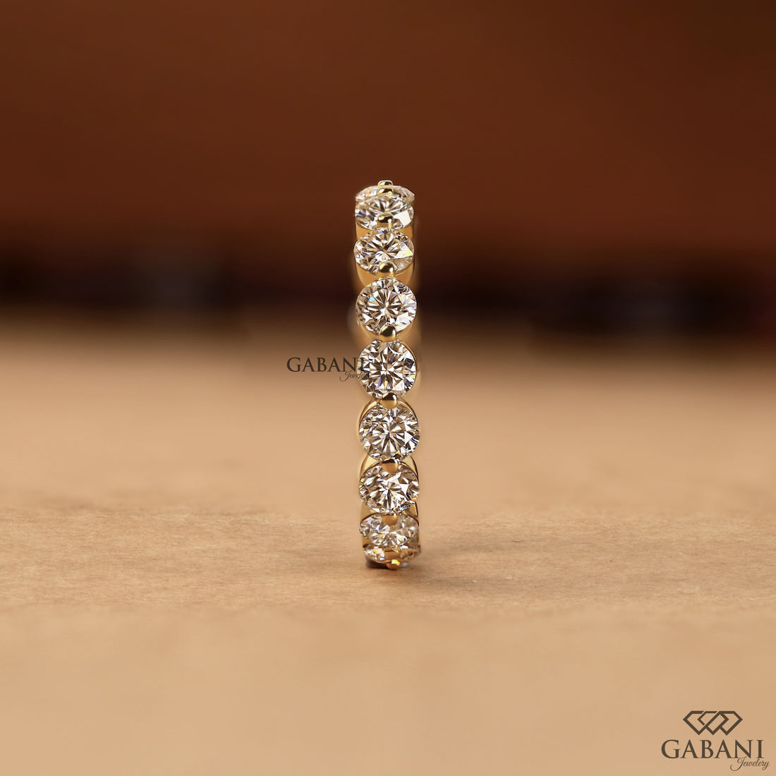 Round lab grown diamond shared prong full eternity wedding band in yellow gold with continuous diamond setting.