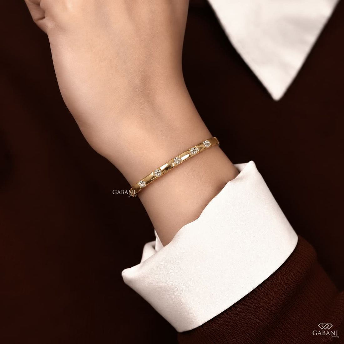 a round lab grown diamond bangle bracelet in yellow gold, featuring evenly spaced sparkling diamonds between polished gold bars in a modern geometric design by Gabani Jewelry.