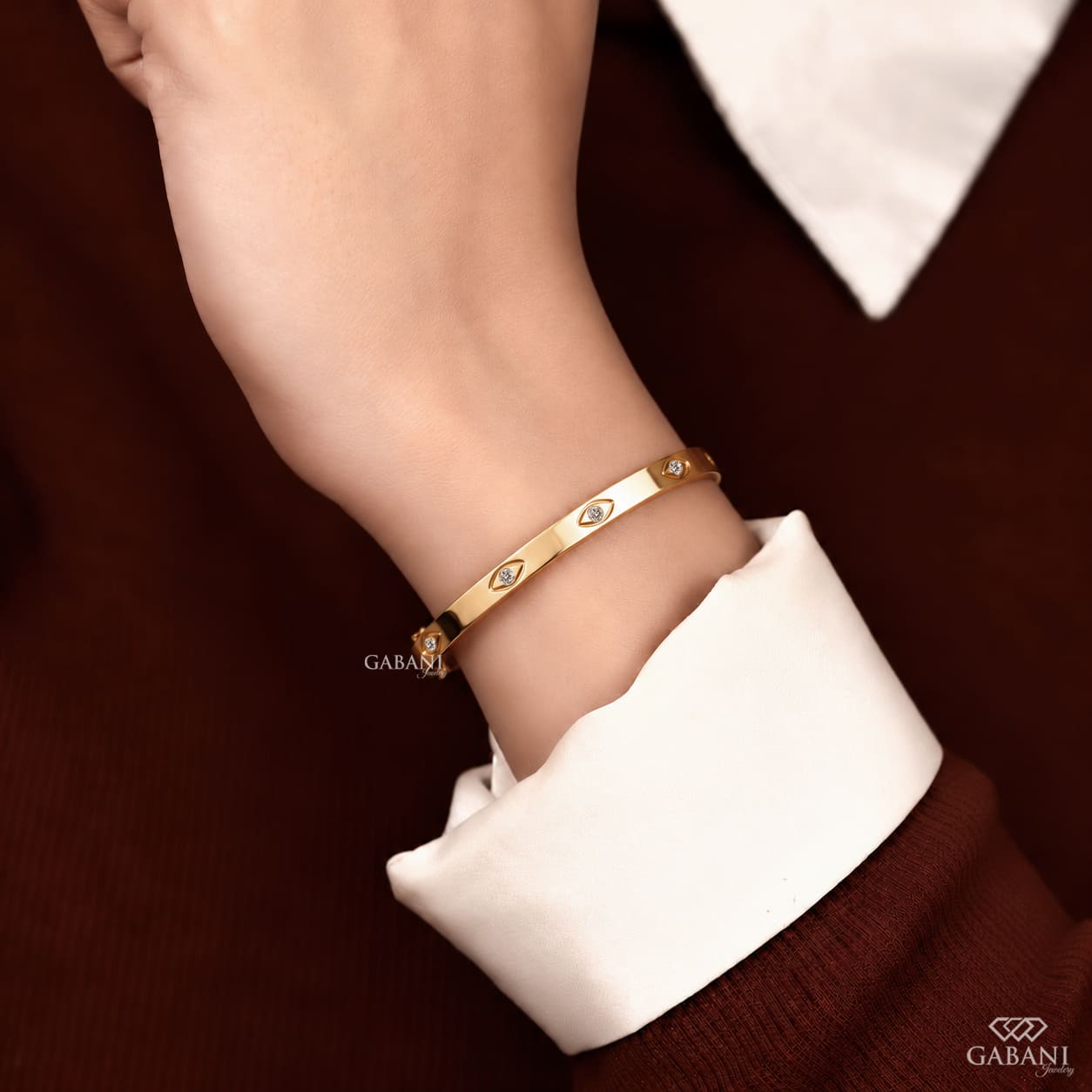 a round lab grown diamond station bangle bracelet in yellow gold, featuring evenly spaced round diamonds in polished bezel-style settings.
