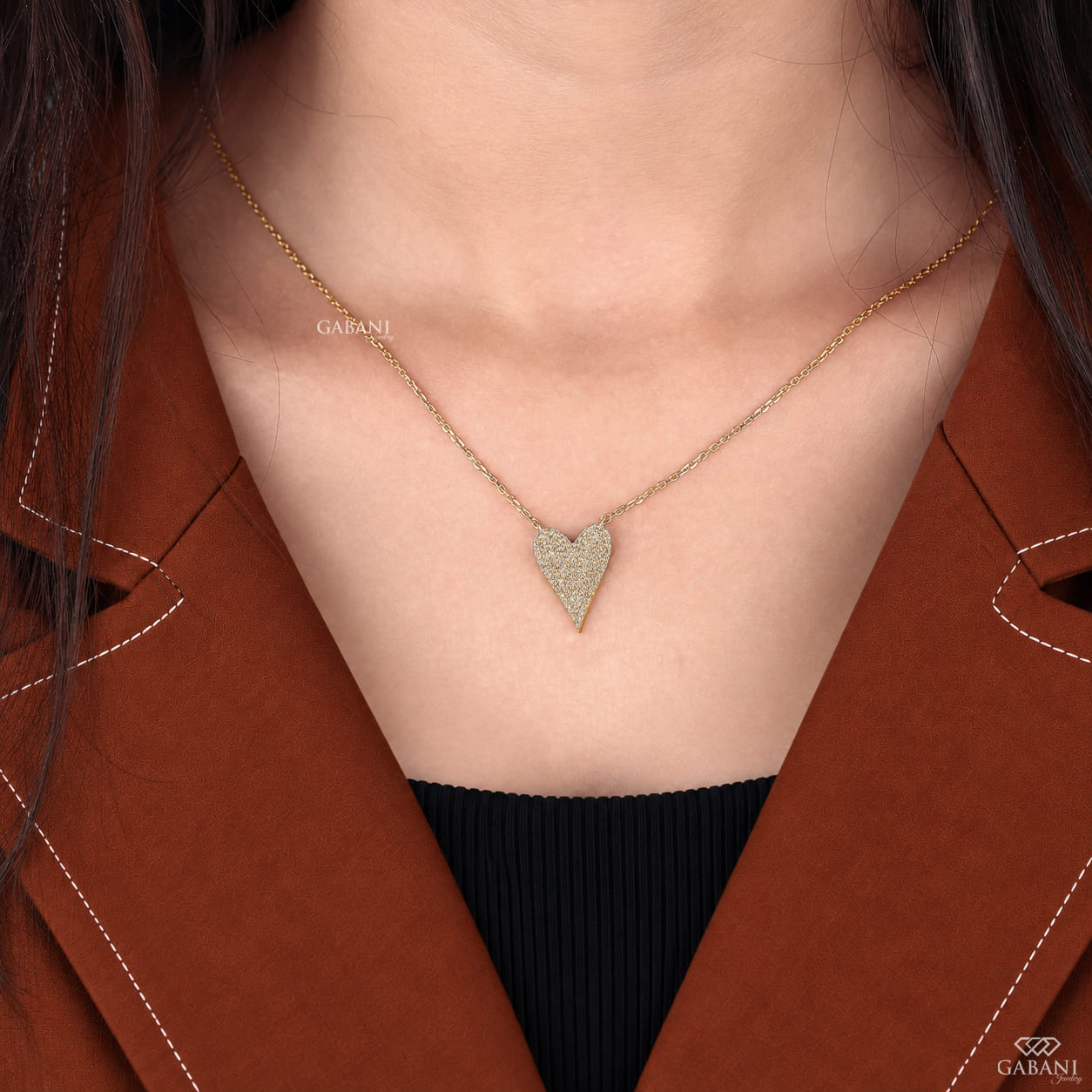 Close-up of an asymmetrical heart shaped lab grown diamond necklace featuring round cut pavé diamonds set in yellow gold.