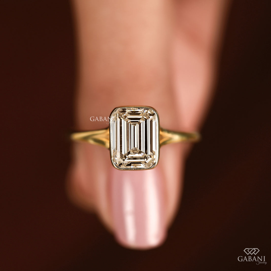 emerald cut diamond solitaire engagement ring with full bezel setting in yellow gold
