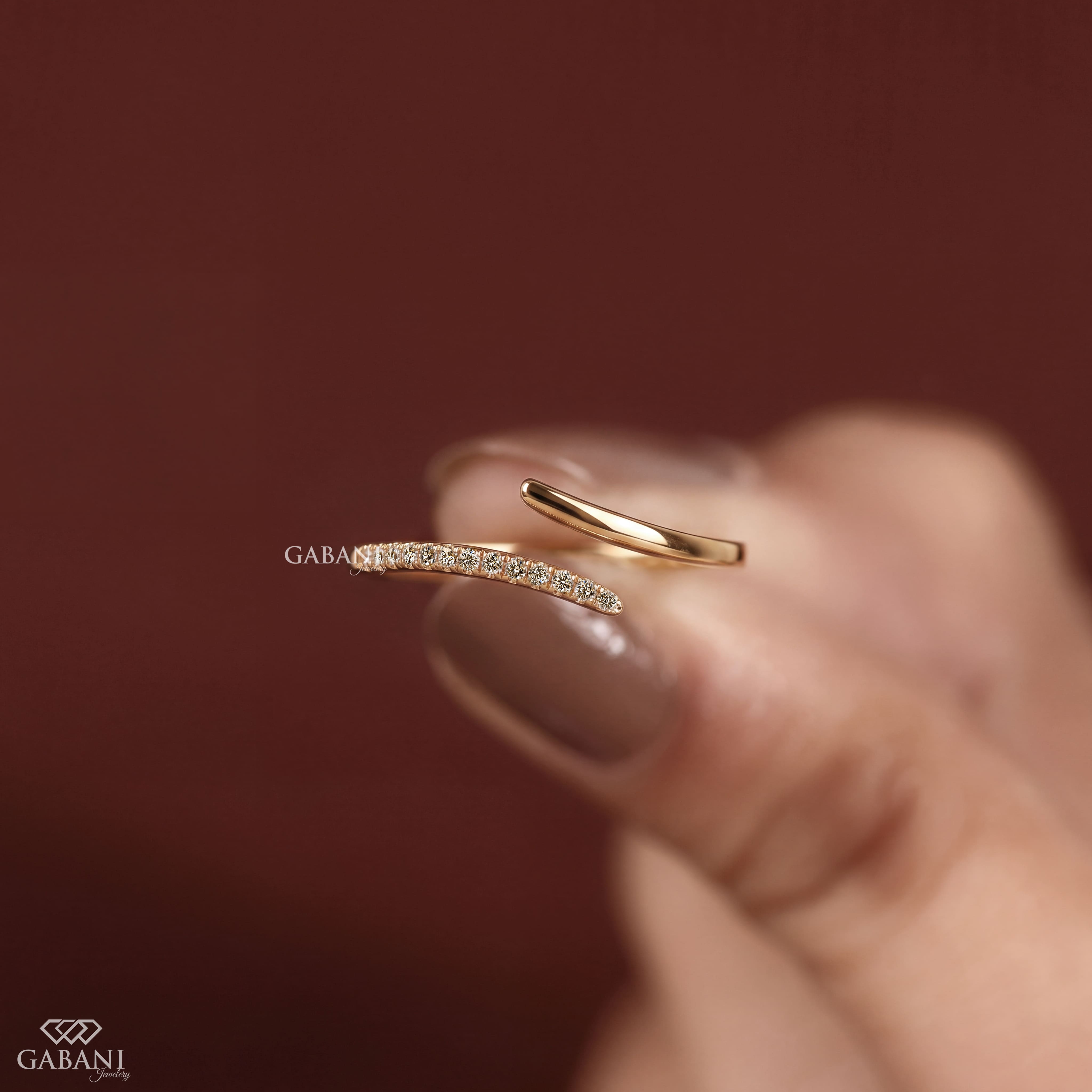 a round lab grown diamond open cuff bangle bracelet in 14K yellow gold, featuring sparkling round diamonds along one curved end and a smooth polished gold wrap design by Gabani Jewelry.