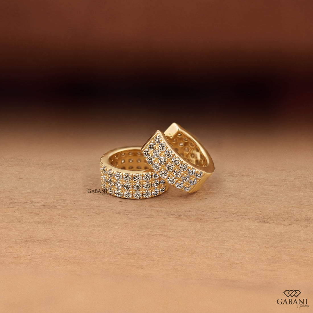 Yellow gold huggie hoop earrings with three rows of round diamonds across the front
