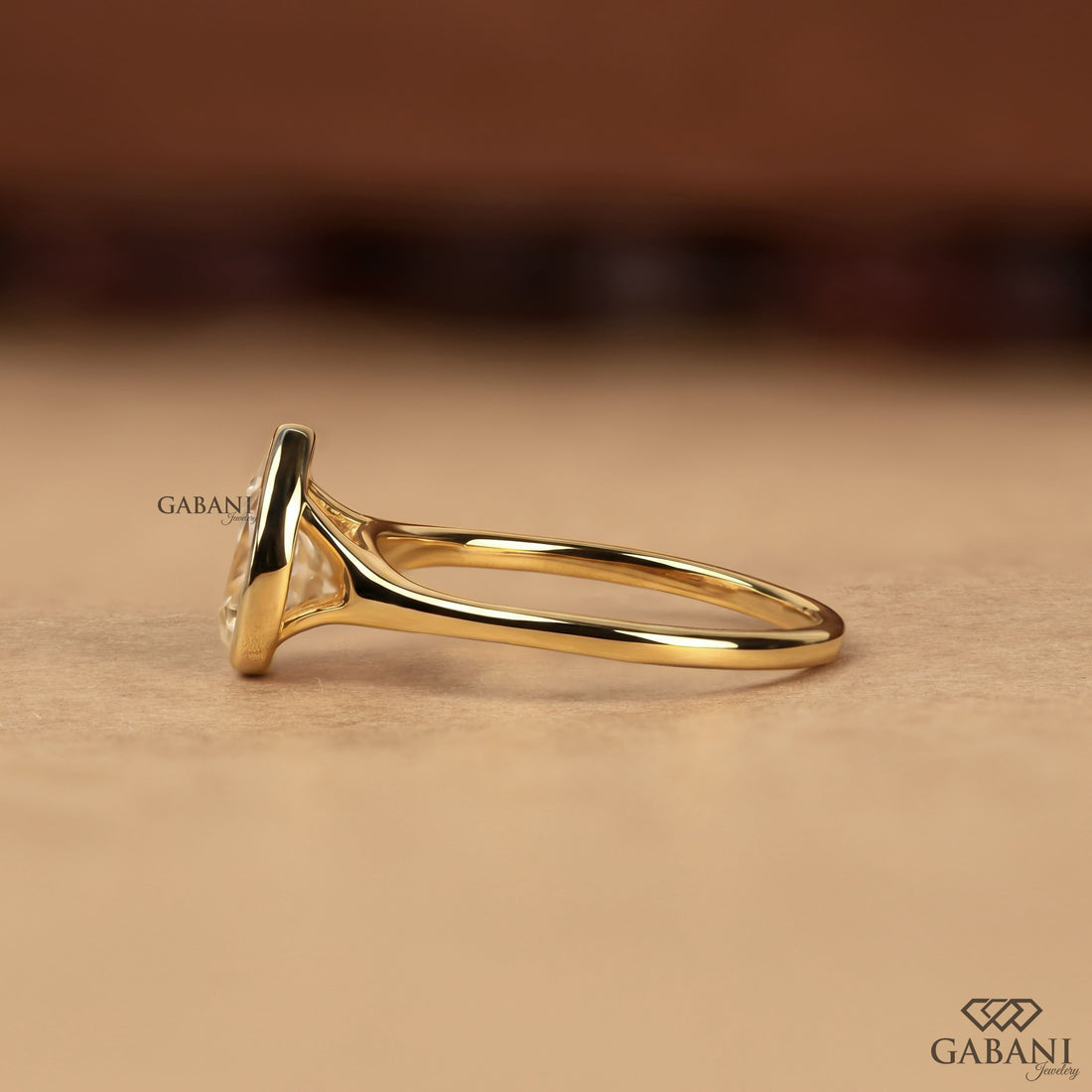 Pear cut diamond solitaire engagement ring with full bezel setting in polished yellow gold
