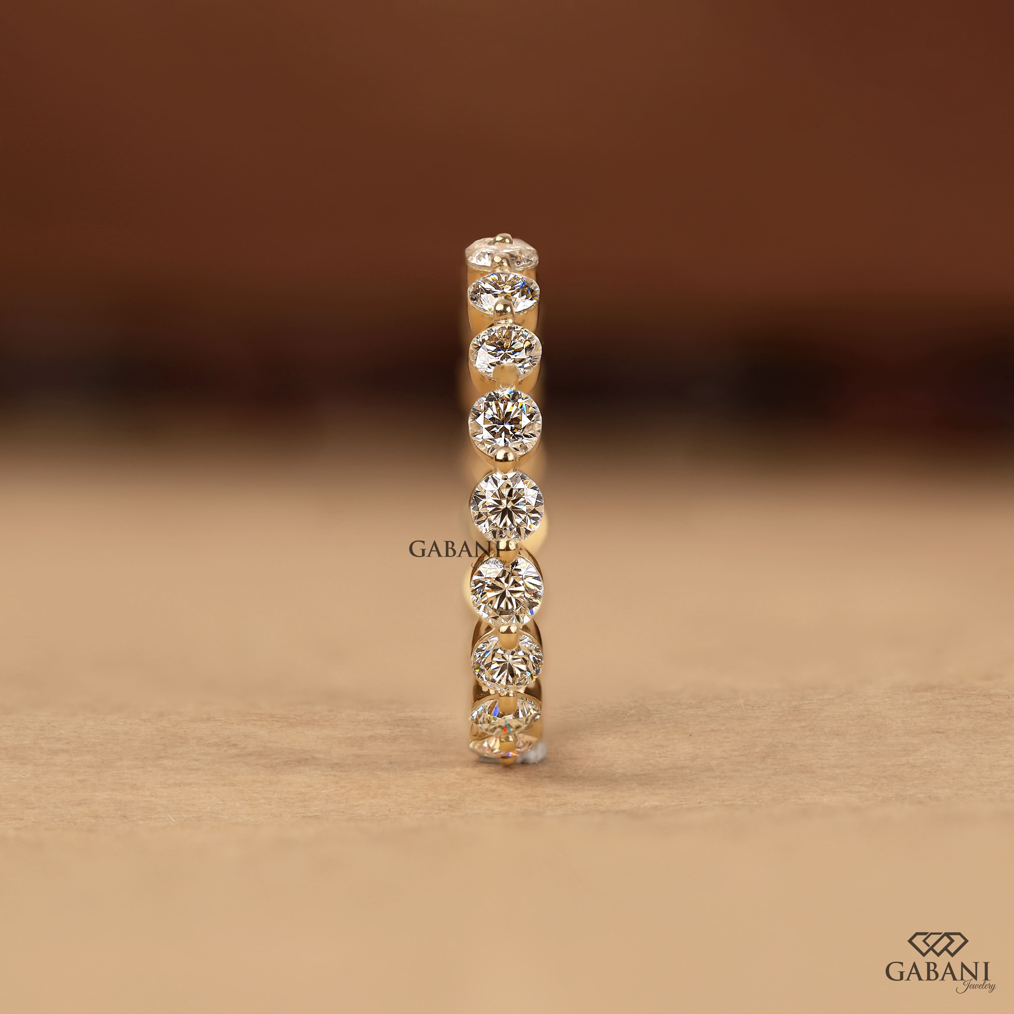 Round cut lab grown diamond full eternity wedding band in yellow gold with shared prong setting.