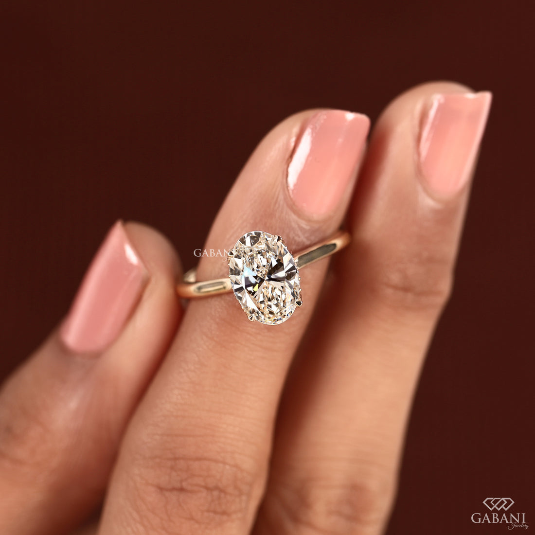 Hand model wearing an oval cut lab grown diamond solitaire ring featuring an IGI Certified center diamond in a hidden halo setting for everyday elegance.