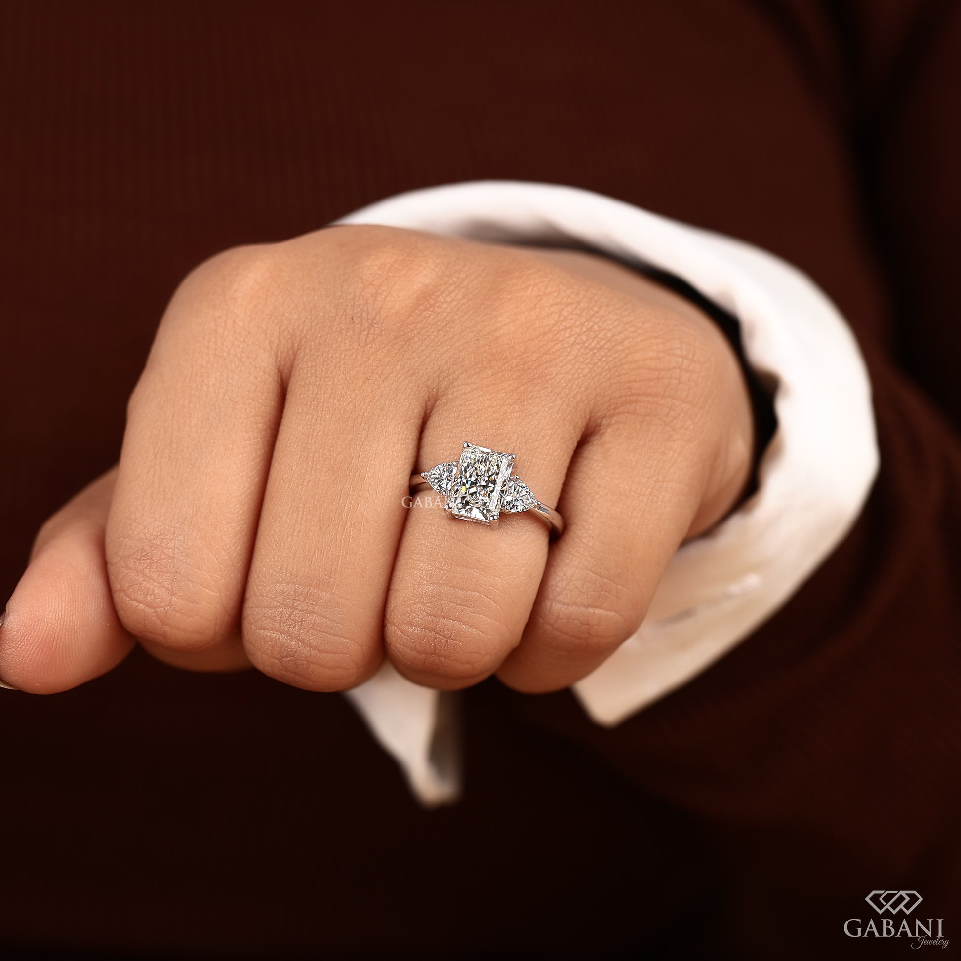 Radiant cut center diamond ring with heart shaped side stones in white gold three stone design