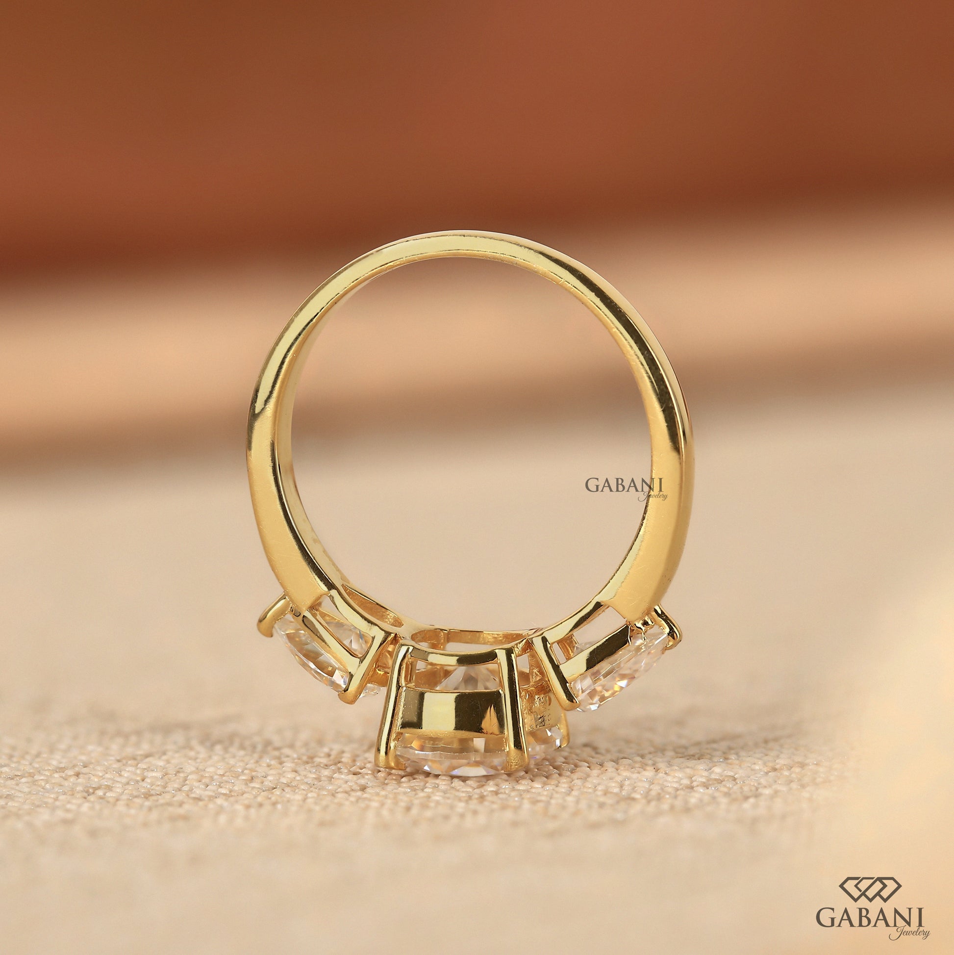 three stone lab grown diamond ring in yellow gold with round center and pear side stones