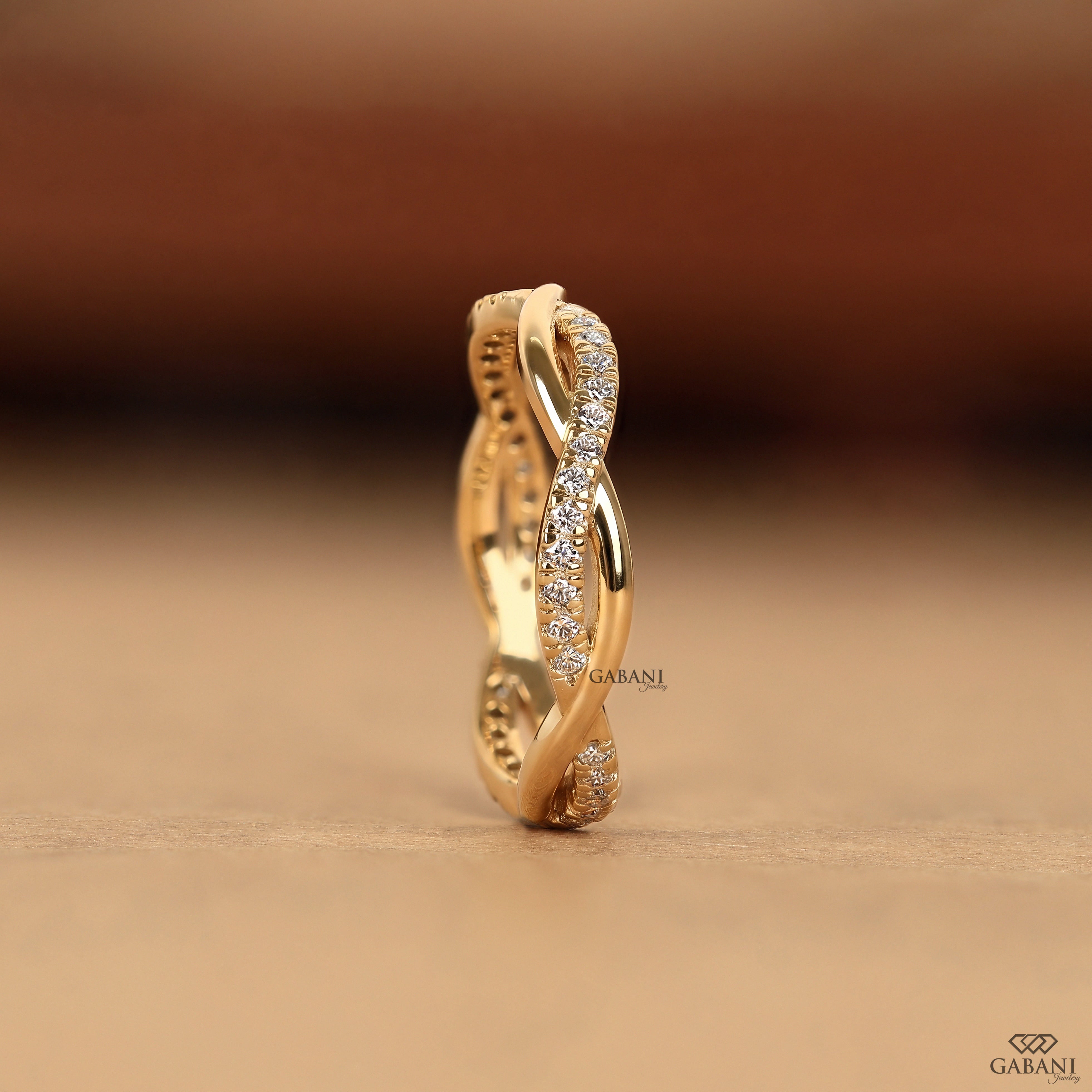 Twisted full eternity lab grown diamond band in yellow gold with round cut diamonds and an infinity inspired crossover design for wedding, anniversary, and stackable wear.