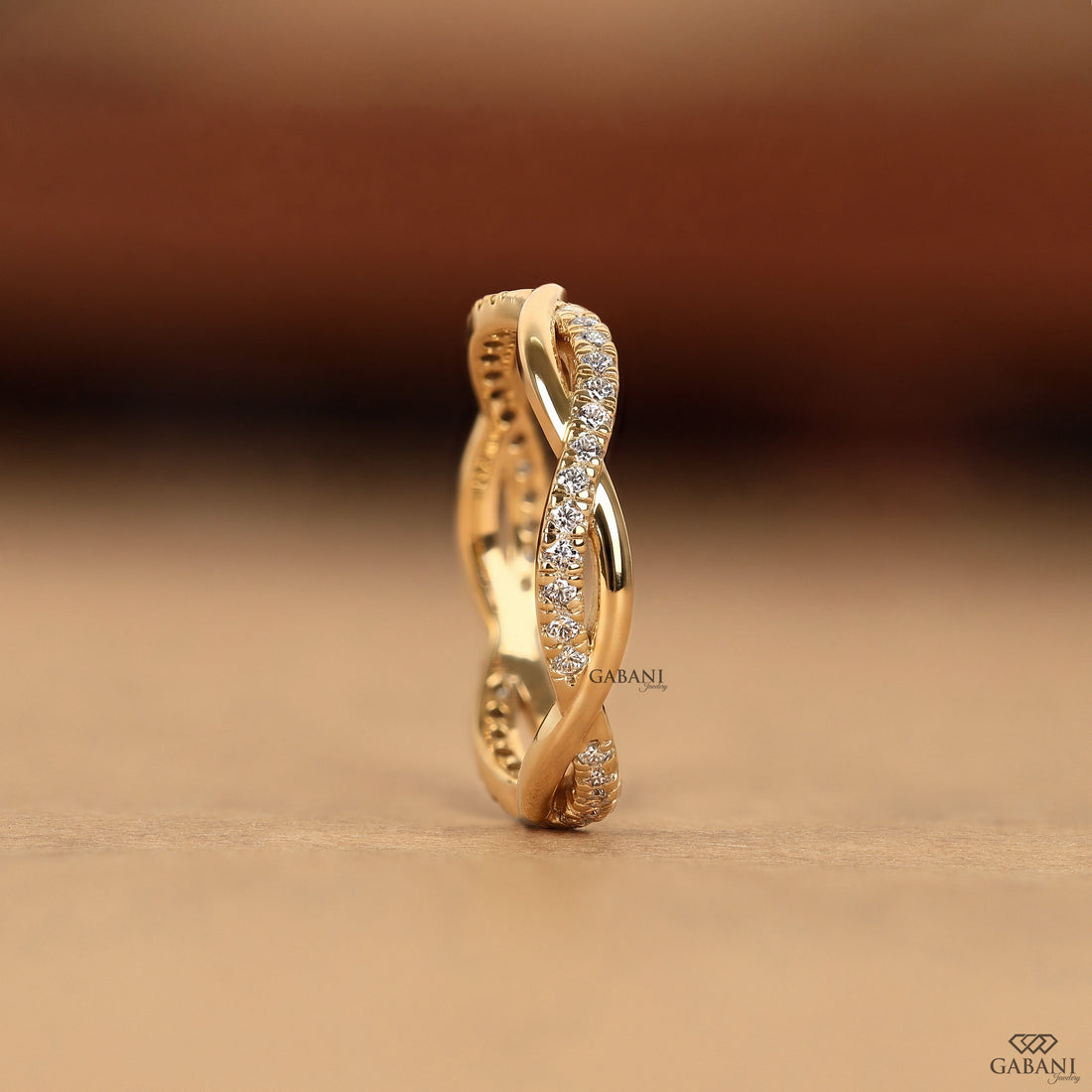 Twisted full eternity lab grown diamond band in yellow gold with round cut diamonds and an infinity inspired crossover design for wedding, anniversary, and stackable wear.