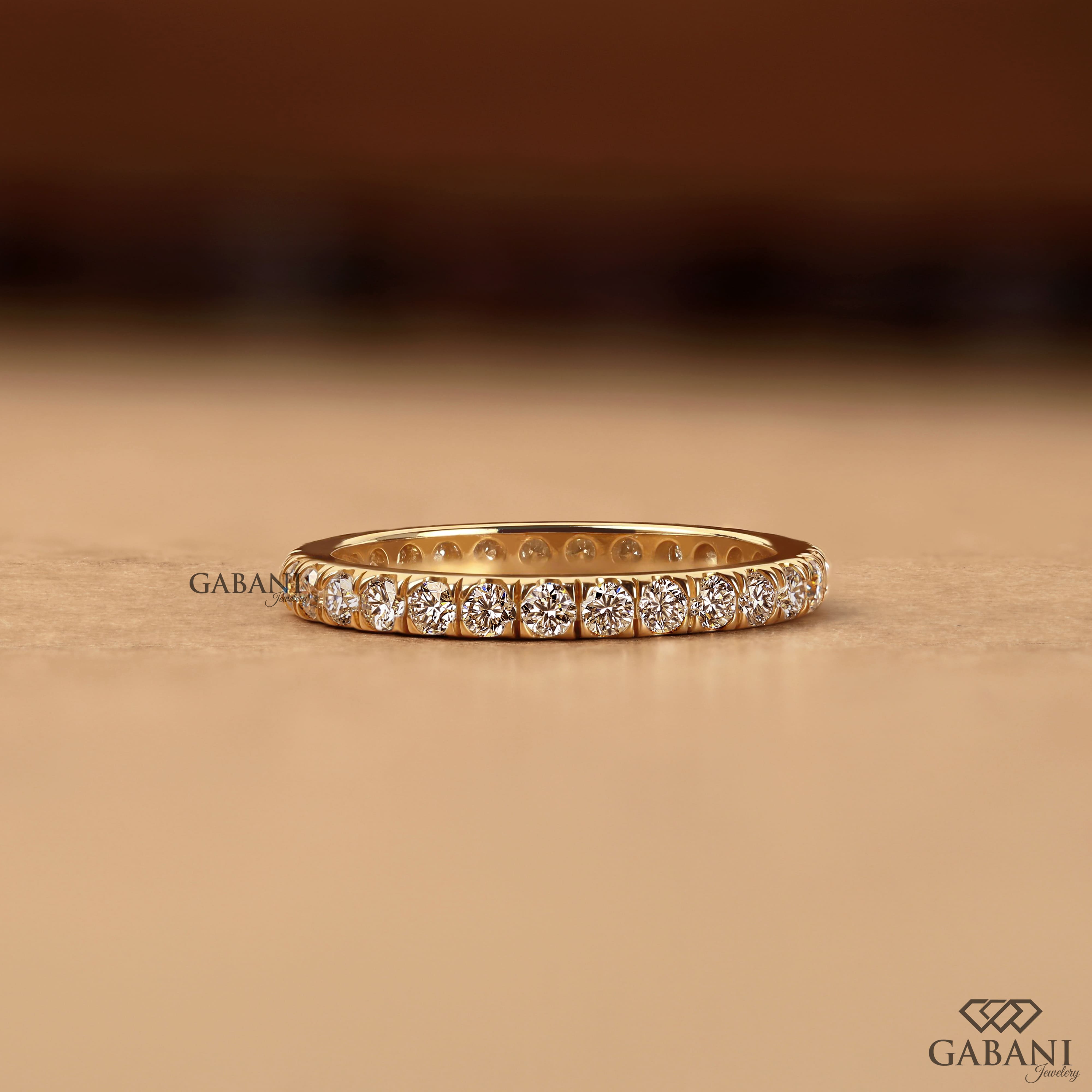 Round cut lab grown diamond eternity wedding band in yellow gold with continuous diamond setting and classic bridal style.