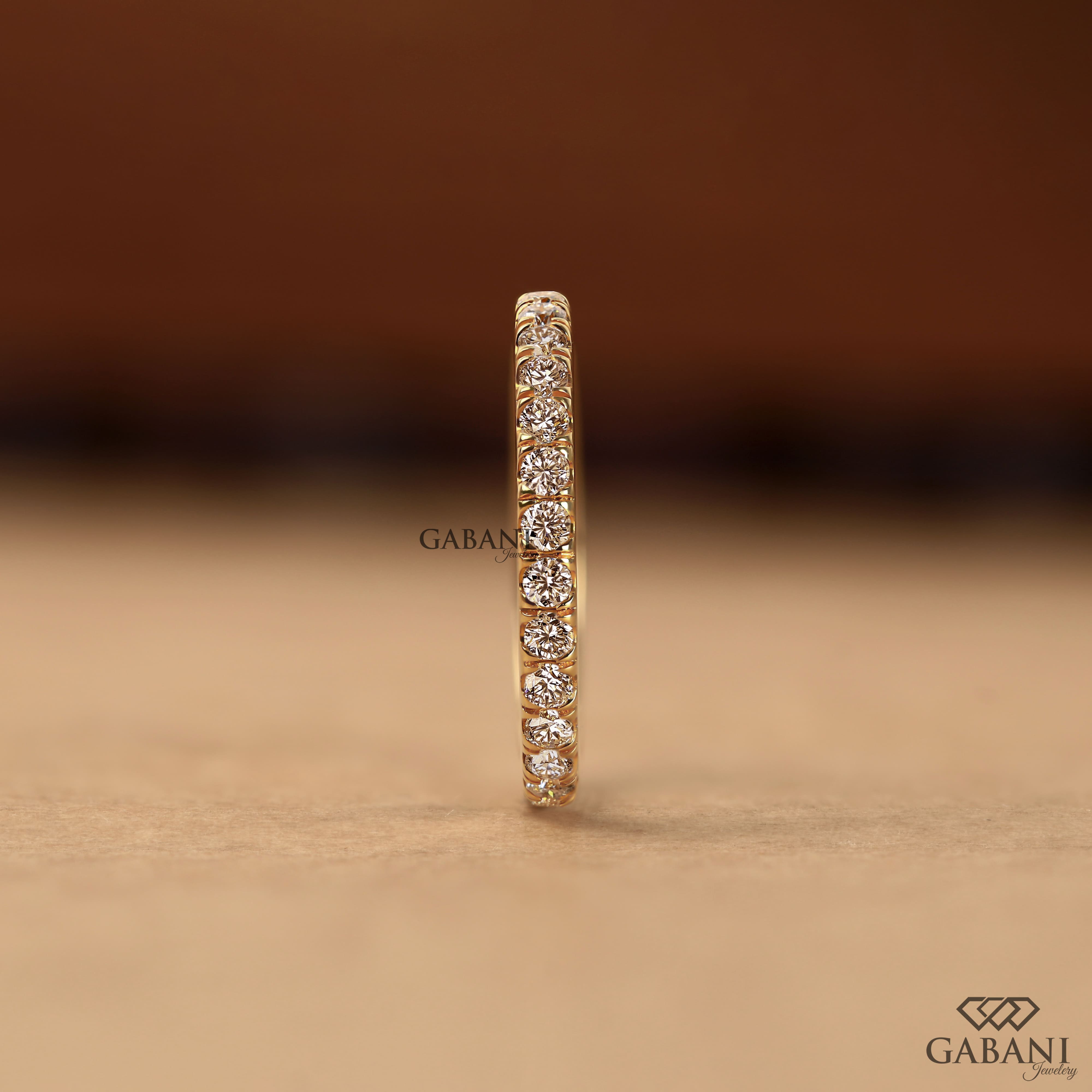 Round cut lab grown diamond eternity wedding band in yellow gold with continuous diamond setting and classic bridal style.