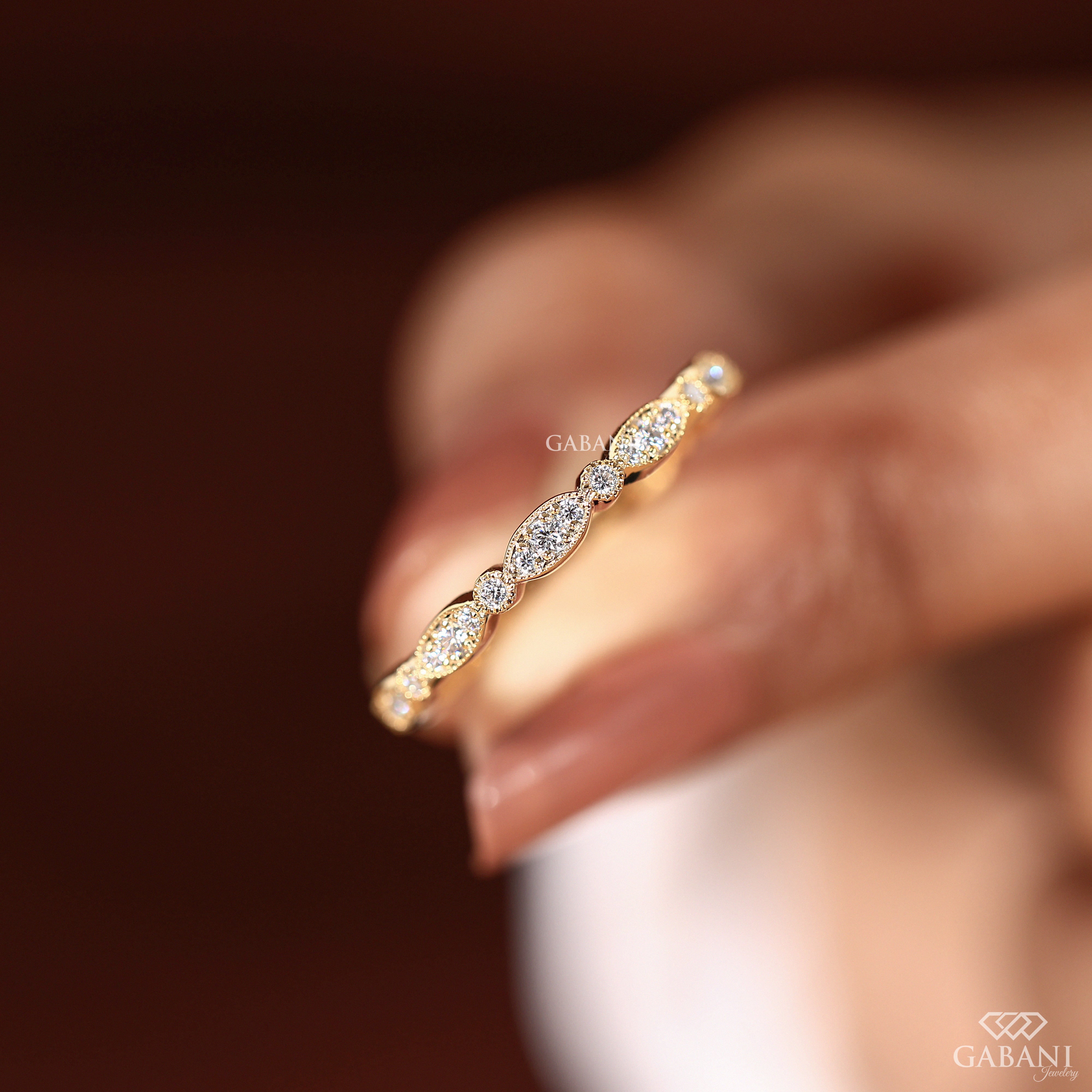 a round cut lab grown diamond wedding band in 14K yellow gold, featuring marquise-inspired diamond clusters, delicate milgrain detailing and a vintage design by Gabani Jewelry.