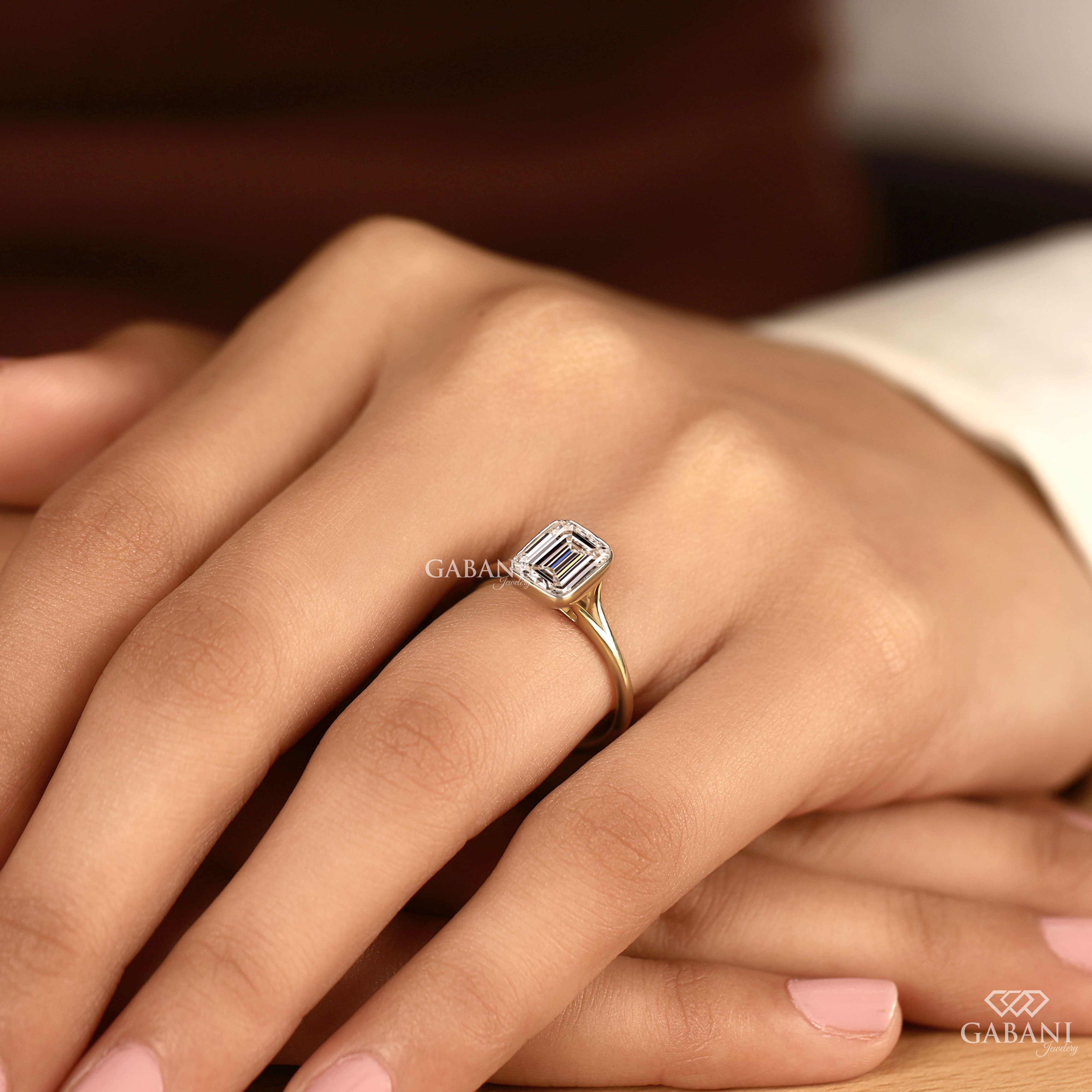 emerald cut diamond solitaire engagement ring with full bezel setting in yellow gold