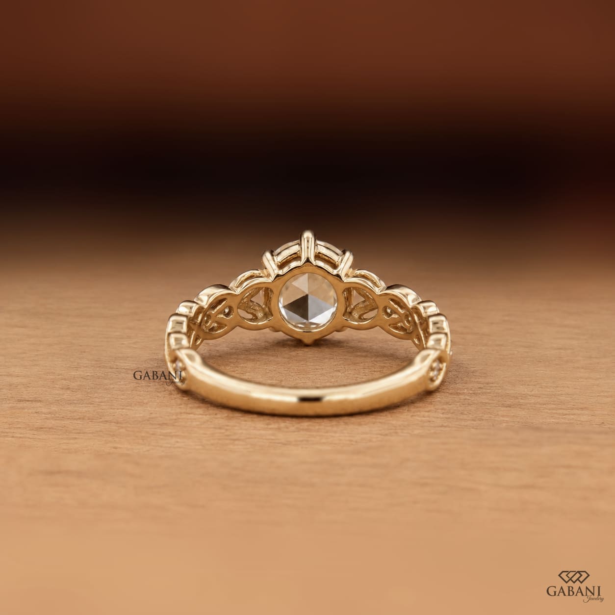 Oval rose cut lab grown diamond engagement ring with leaf vine band, round diamond accents, and six claw prong setting in 14K yellow gold.