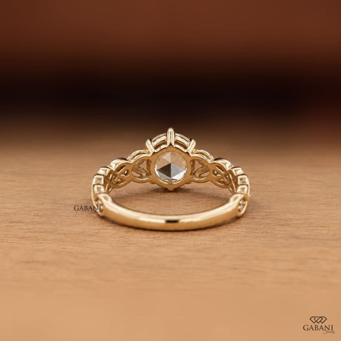 Oval rose cut lab grown diamond engagement ring with leaf vine band, round diamond accents, and six claw prong setting in 14K yellow gold.