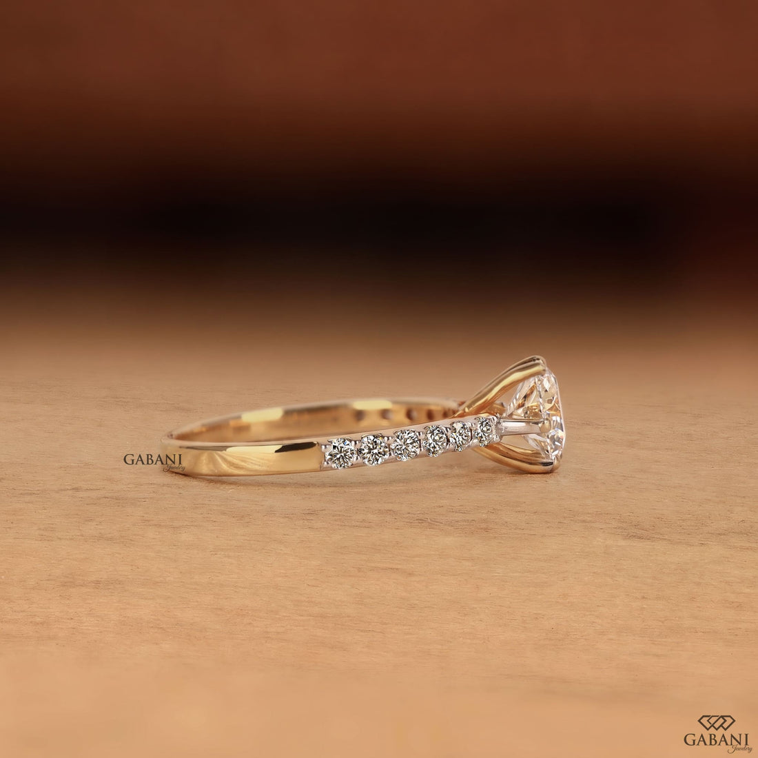 Round cut lab grown diamond solitaire engagement ring in yellow gold featuring a classic six prong setting and pavé diamond band.
