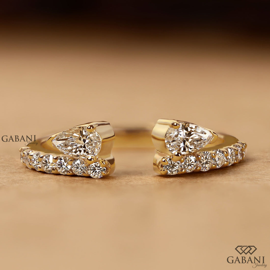 pear cut lab grown diamond open cuff ring showing the partial bezel settings, open ends and polished yellow gold band.