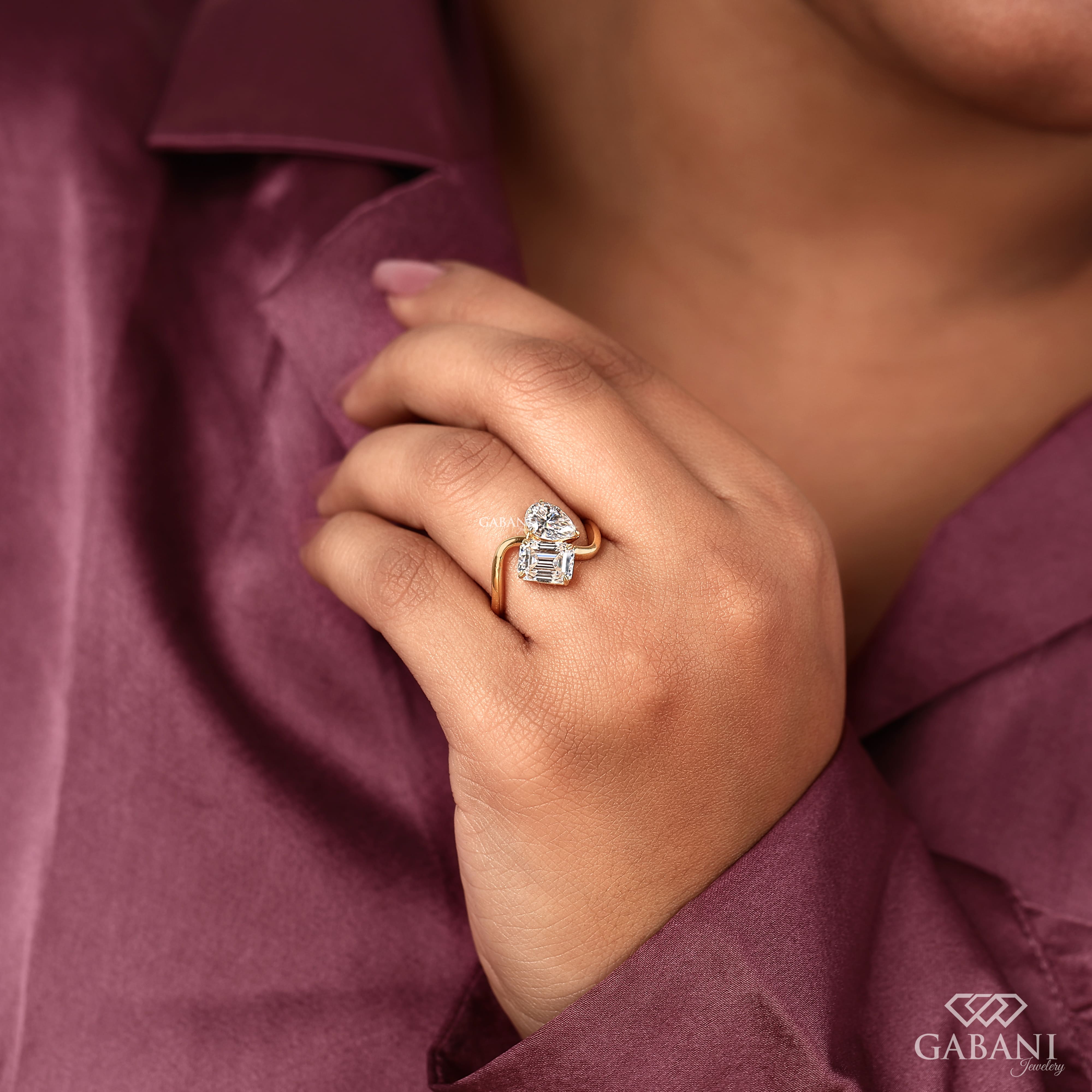 Pear and emerald cut lab grown diamond Toi et Moi ring with a curved yellow gold band, designed for engagement, anniversary, proposal, and statement wear.