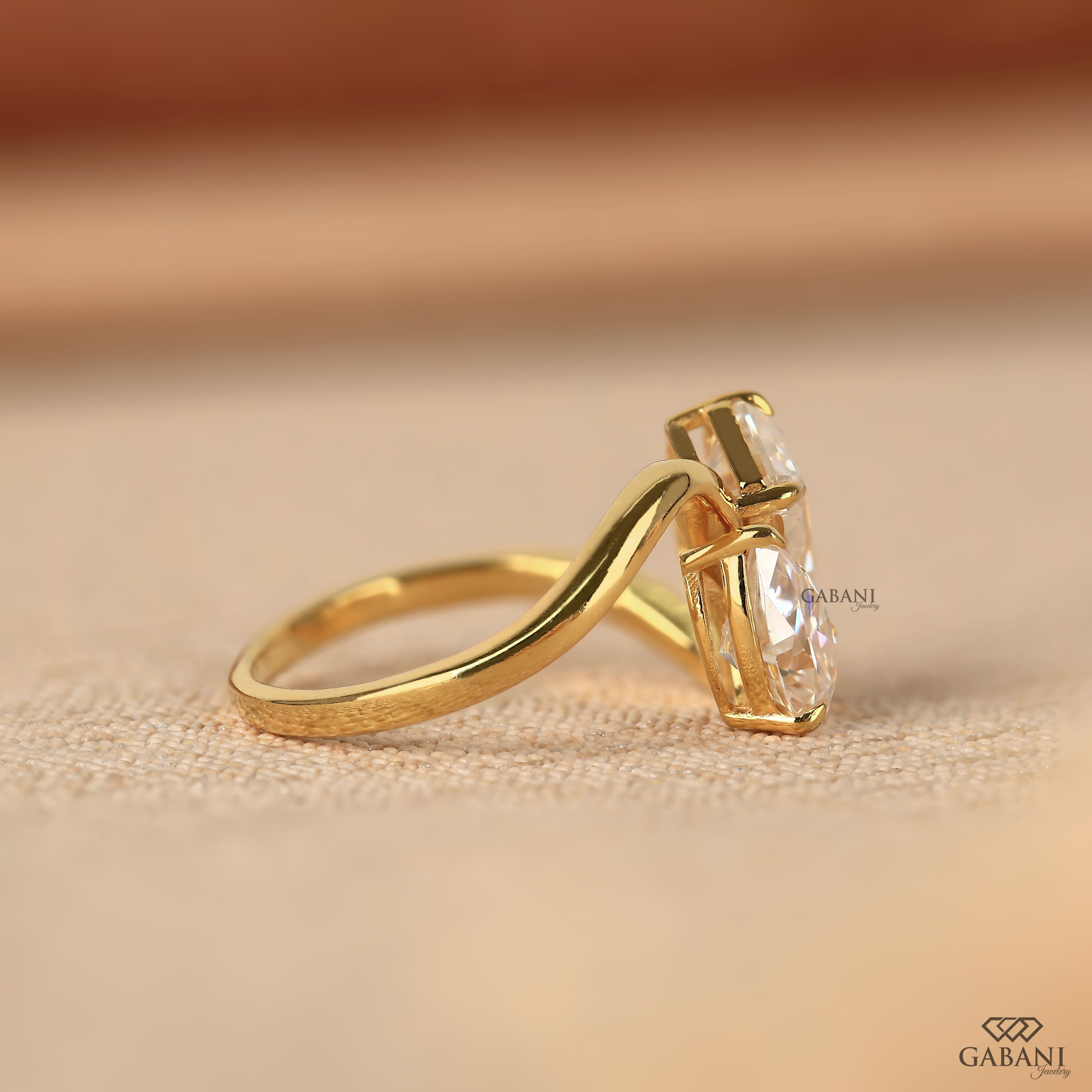 Pear and emerald cut lab grown diamond Toi et Moi ring with a curved yellow gold band, designed for engagement, anniversary, proposal, and statement wear.