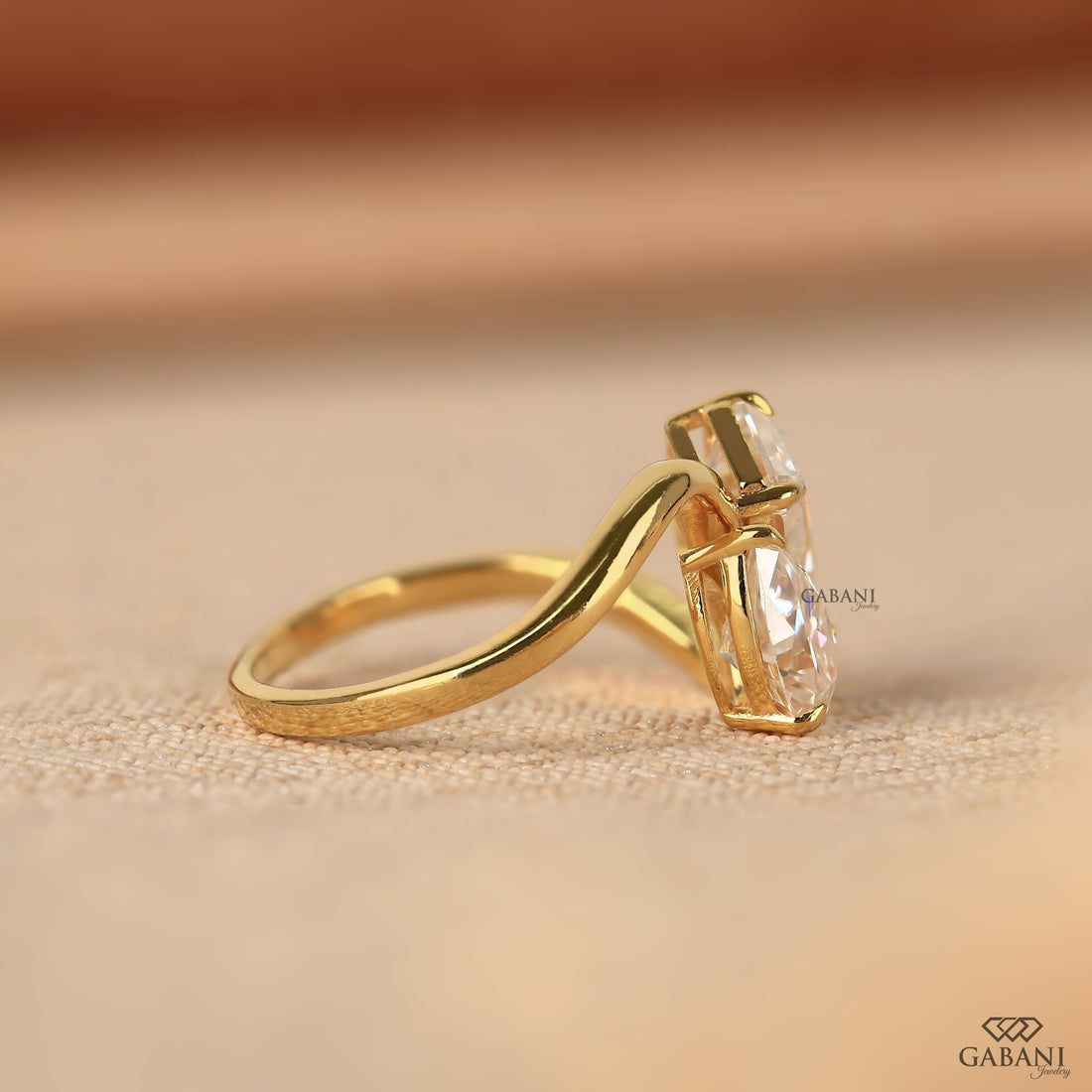 Pear and emerald cut lab grown diamond Toi et Moi ring with a curved yellow gold band, designed for engagement, anniversary, proposal, and statement wear.
