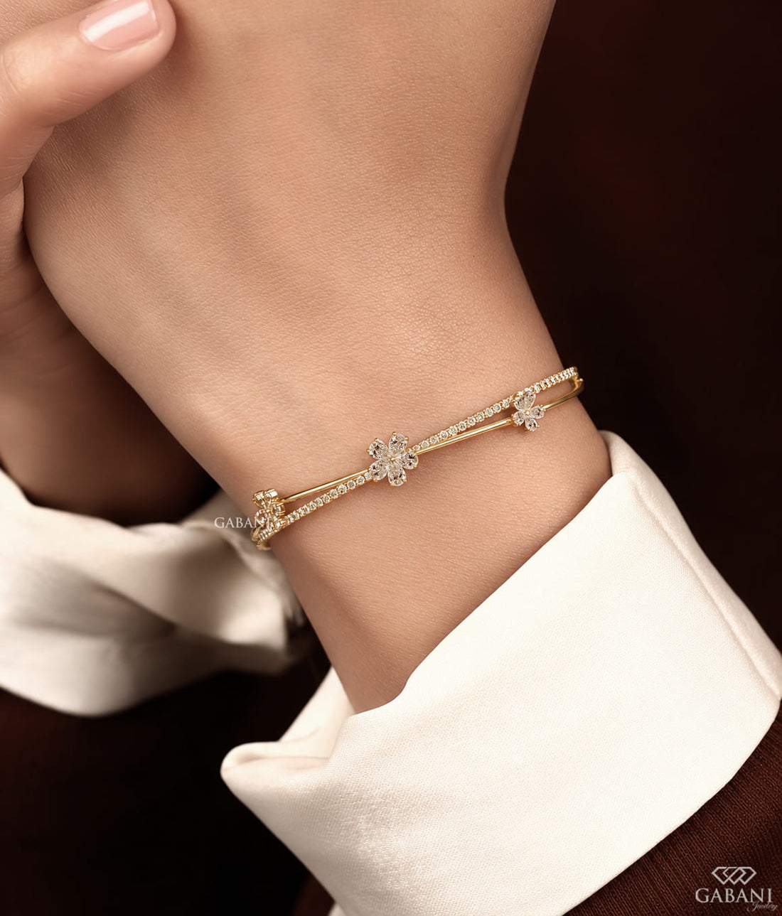 Yellow gold open cuff bangle bracelet featuring three pear cut diamond flower clusters and round pavé diamond accents.