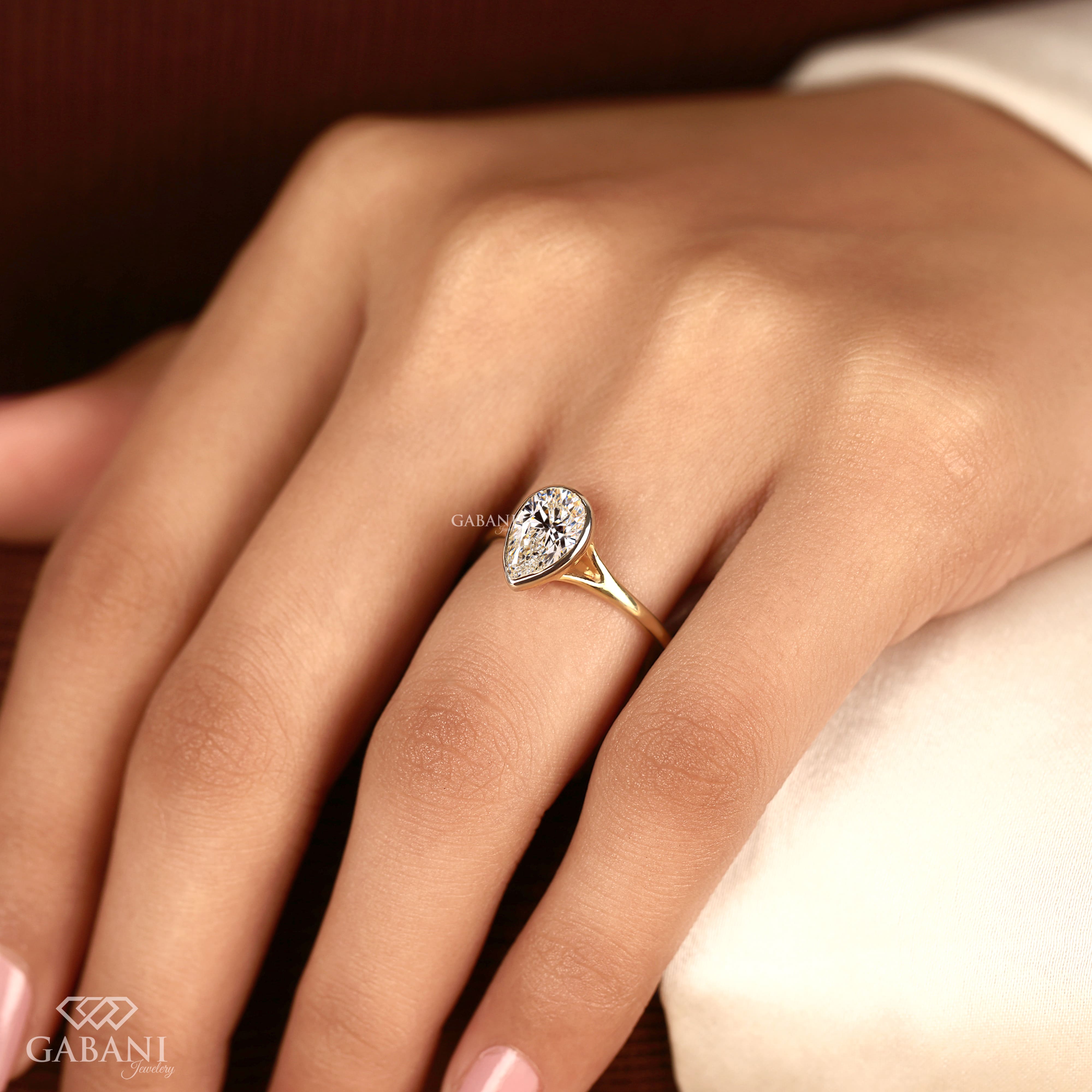 Pear cut diamond solitaire engagement ring with full bezel setting in polished yellow gold