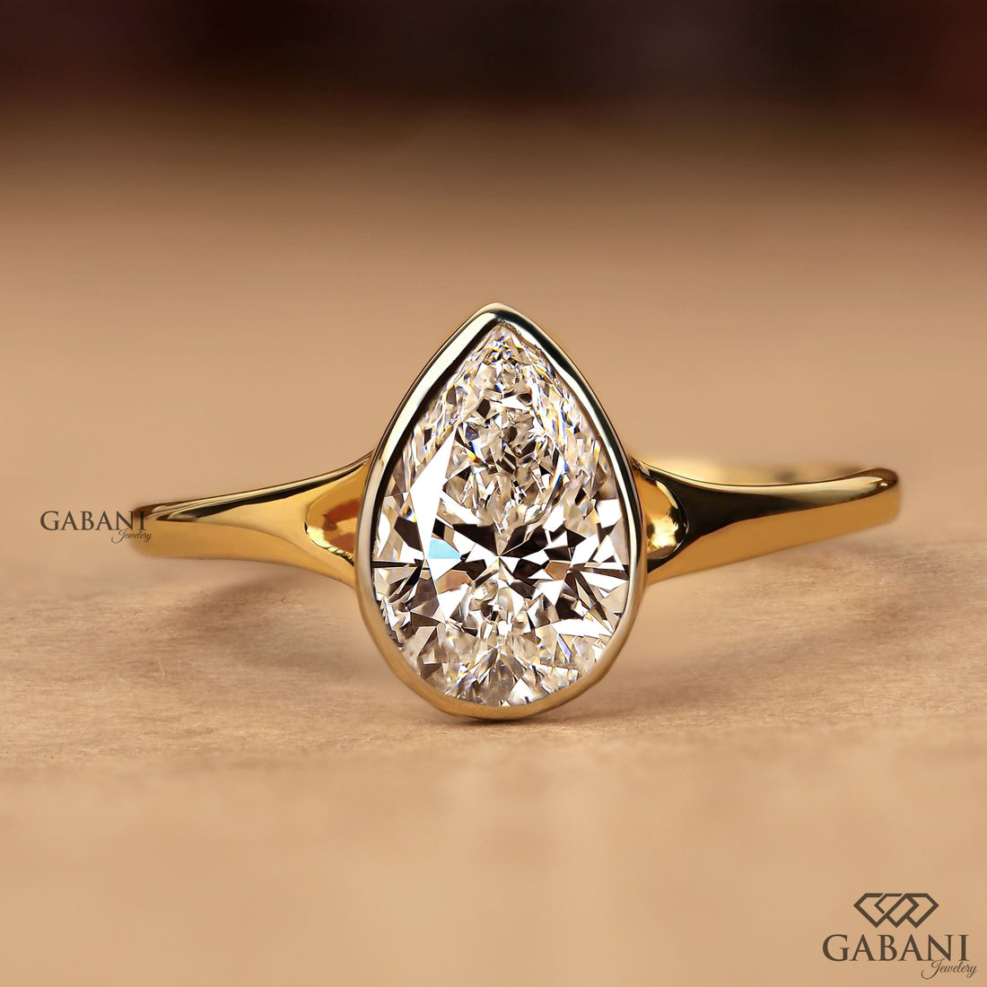 Pear cut diamond solitaire engagement ring with full bezel setting in polished yellow gold