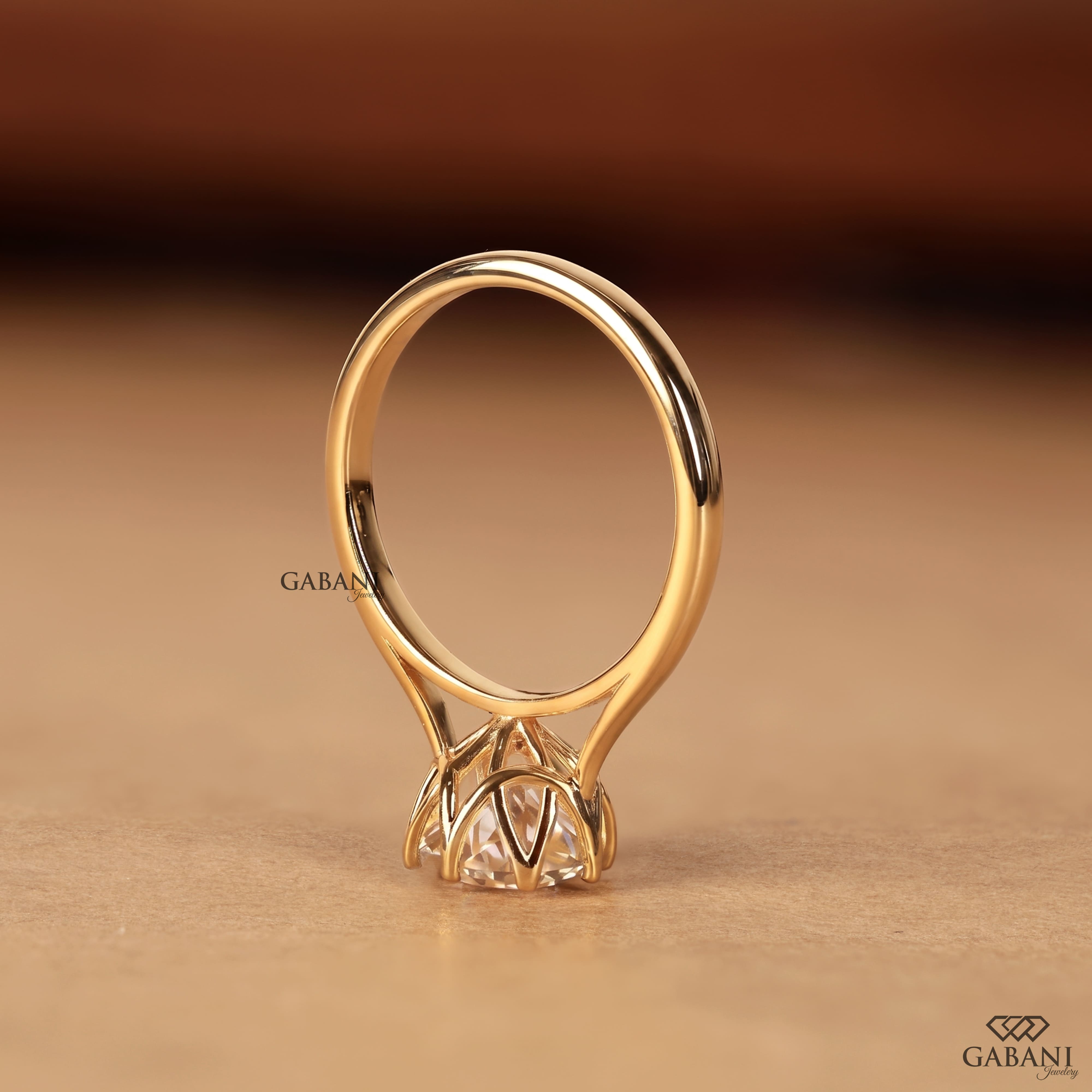 Shop a round Portuguese cut lab grown diamond solitaire engagement ring with a six-prong floral basket and polished yellow gold band.