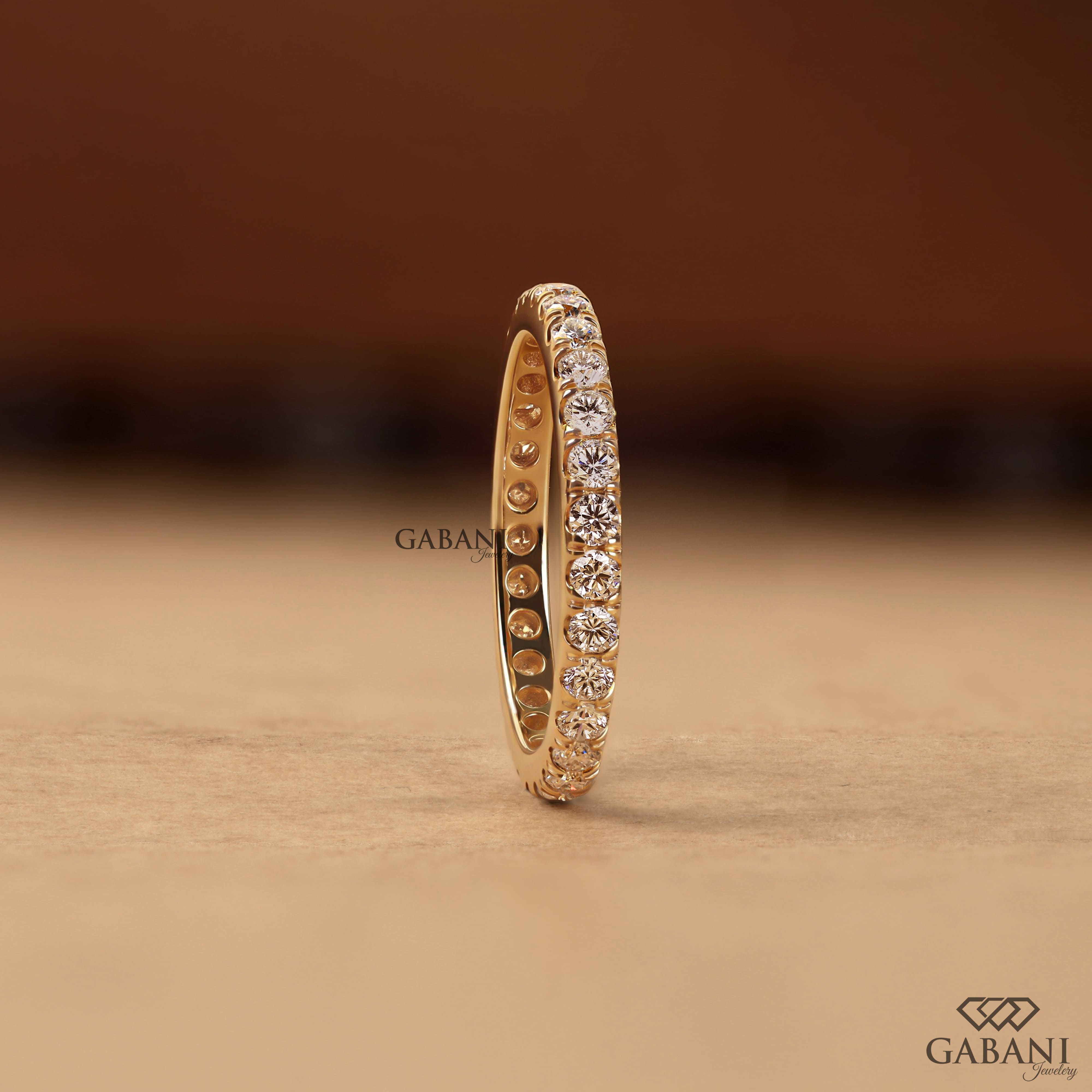 Round cut lab grown diamond eternity wedding band in yellow gold with continuous diamond setting and classic bridal style.