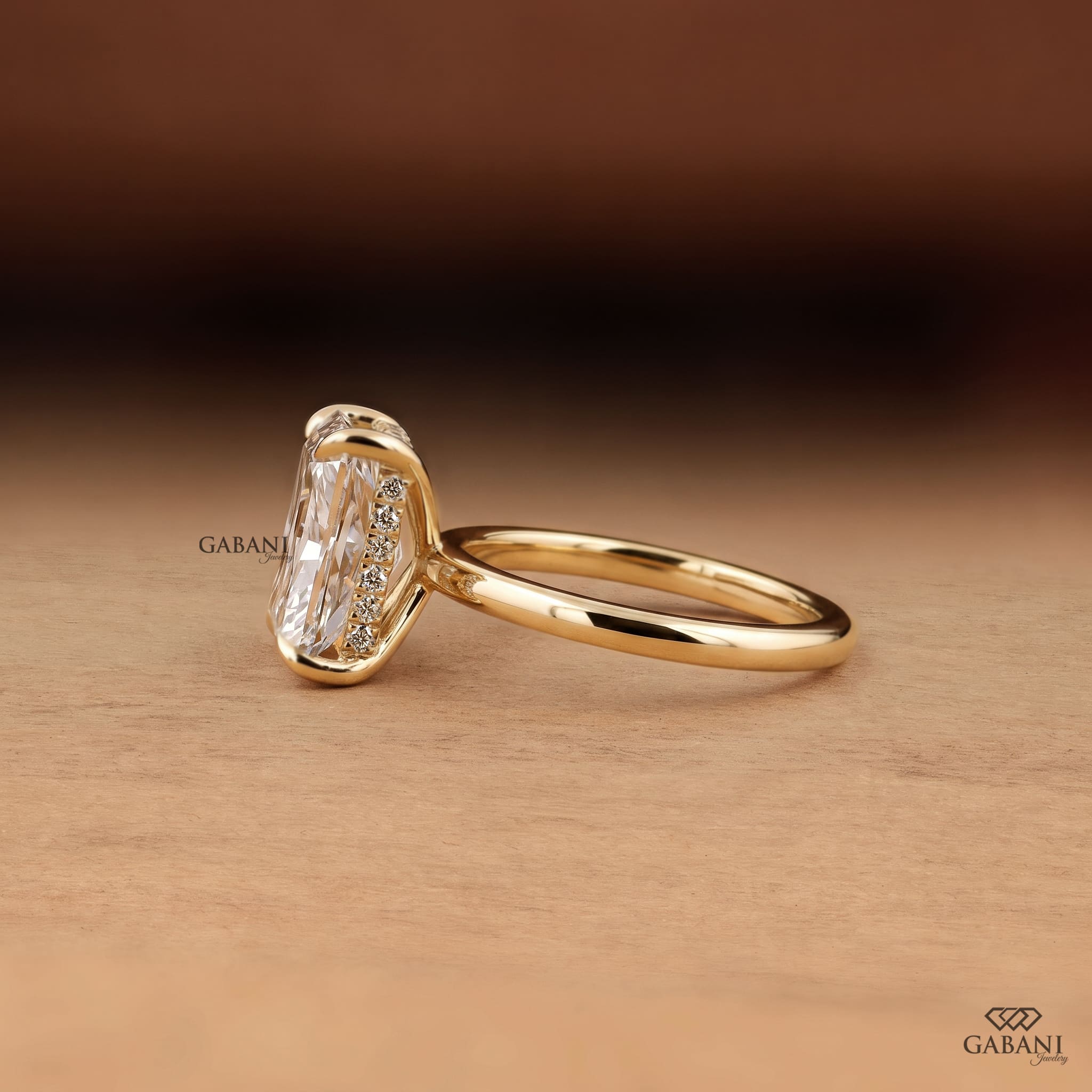 Radiant cut lab grown diamond engagement ring in 18K yellow gold with hidden halo, four claw prong setting and round diamond accents.