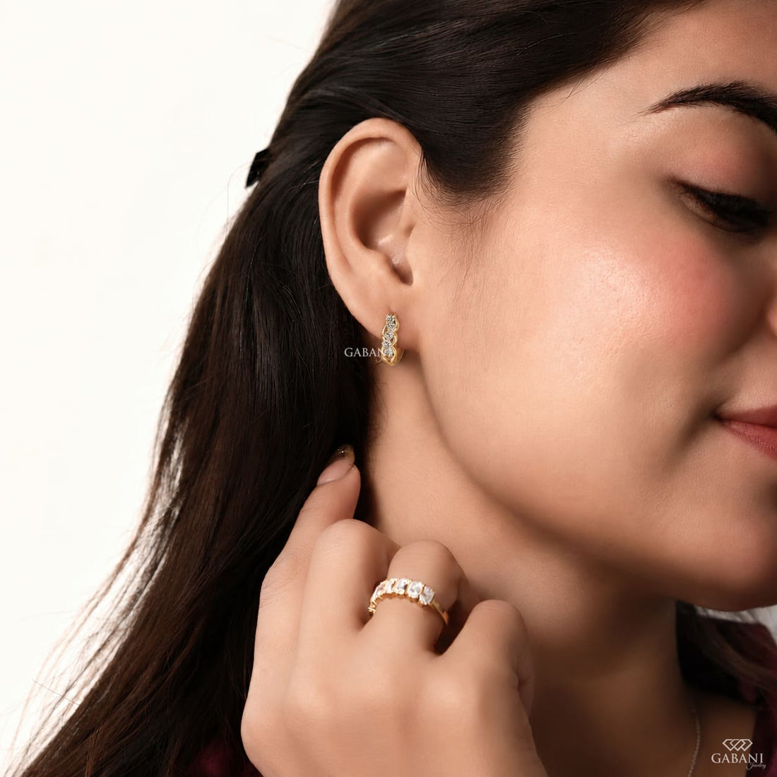 Round diamond infinity huggie hoop earrings in yellow gold with five diamonds and curved gold loop detailing.
