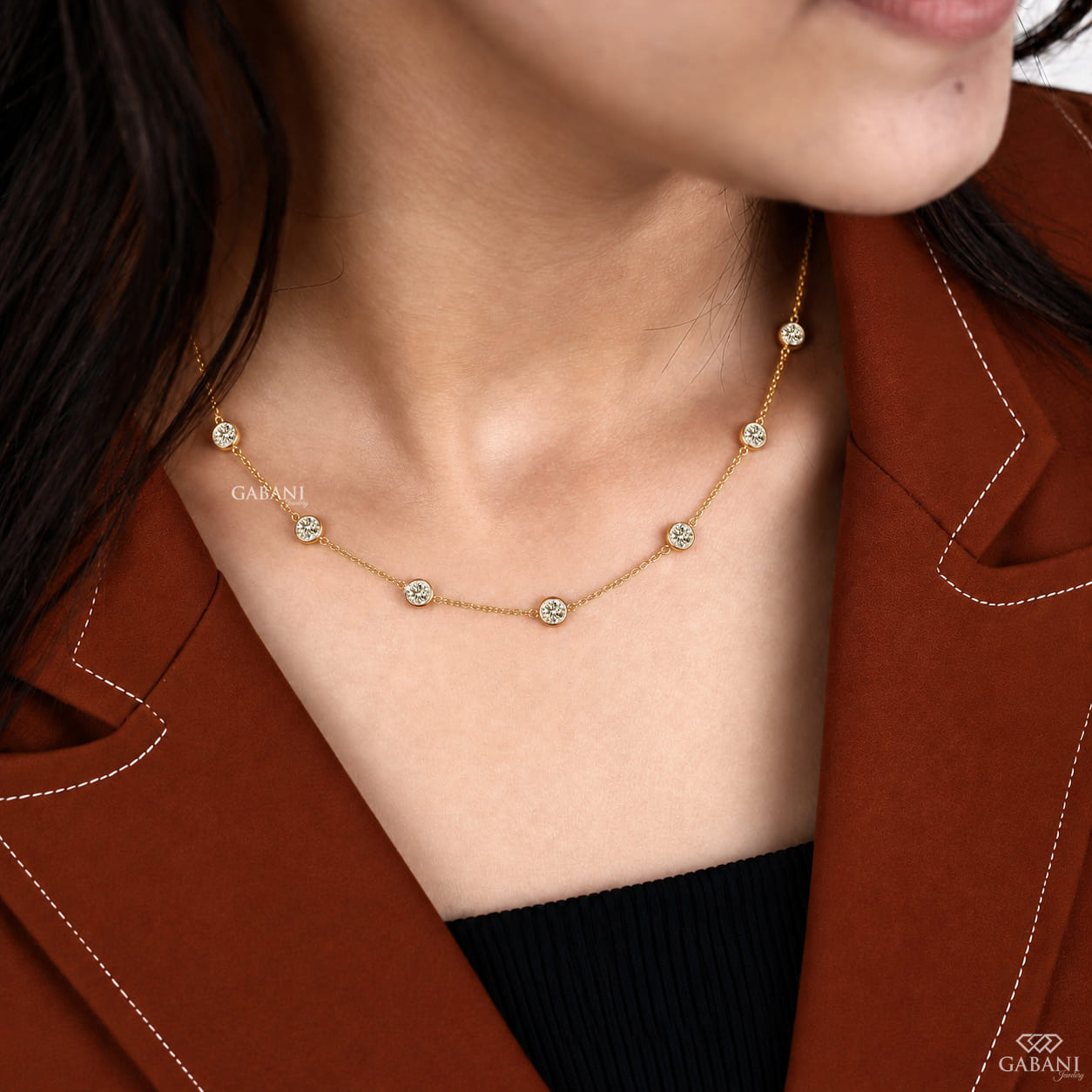 Yellow gold station necklace featuring evenly spaced round cut diamonds in full bezel settings along a delicate gold chain.