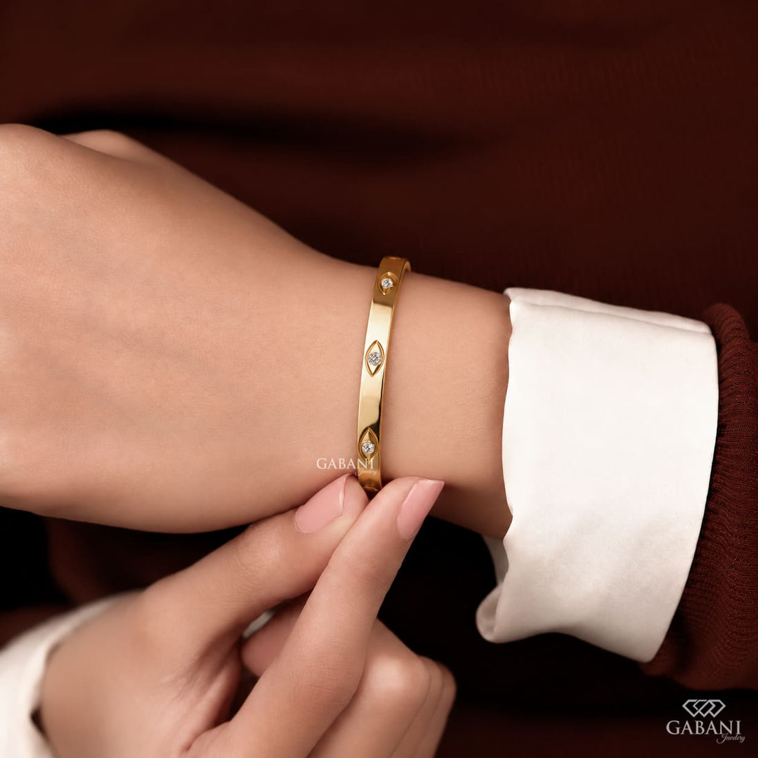 a round lab grown diamond station bangle bracelet in yellow gold, featuring evenly spaced round diamonds in polished bezel-style settings.