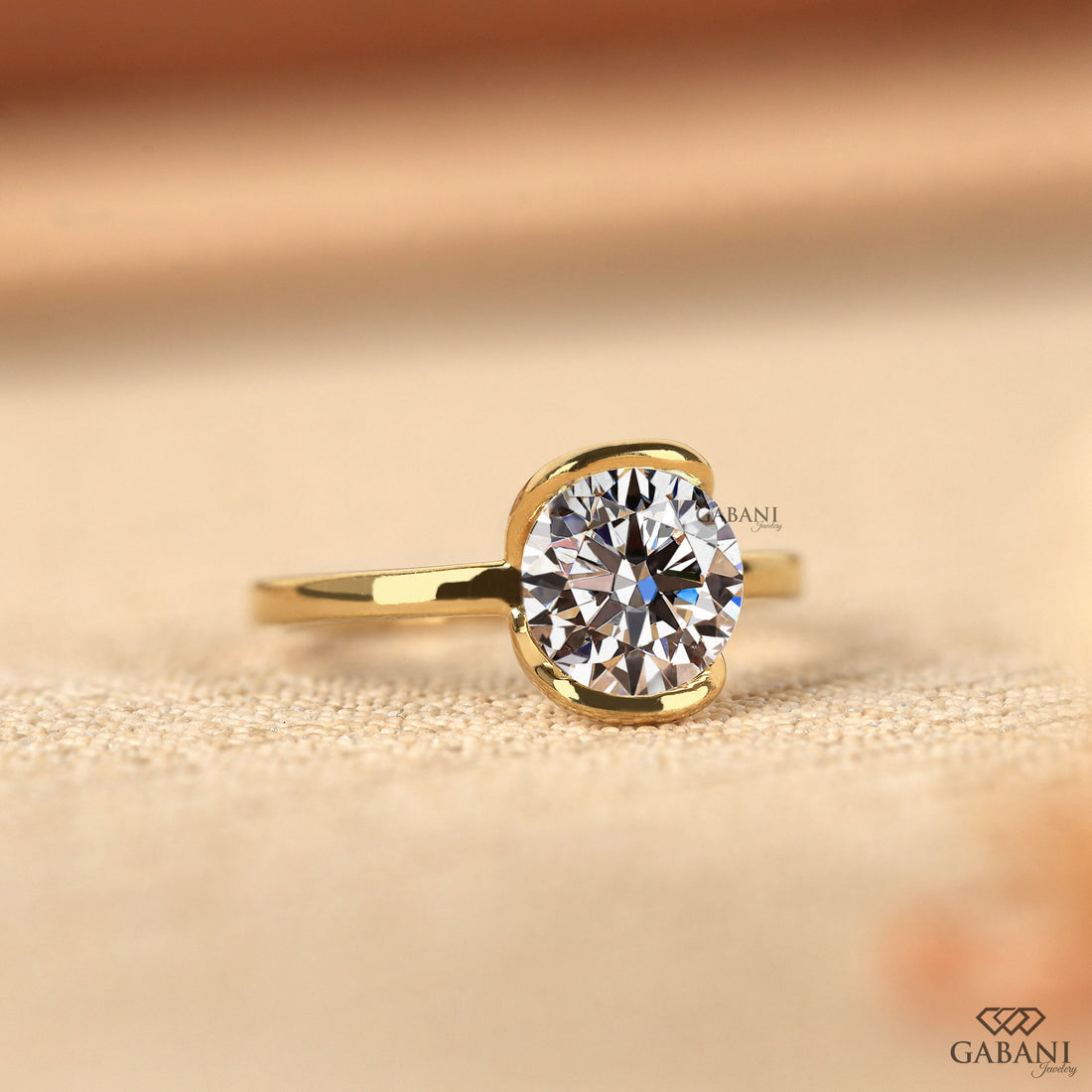 Round diamond half bezel solitaire engagement ring in yellow gold with a slim straight polished band.