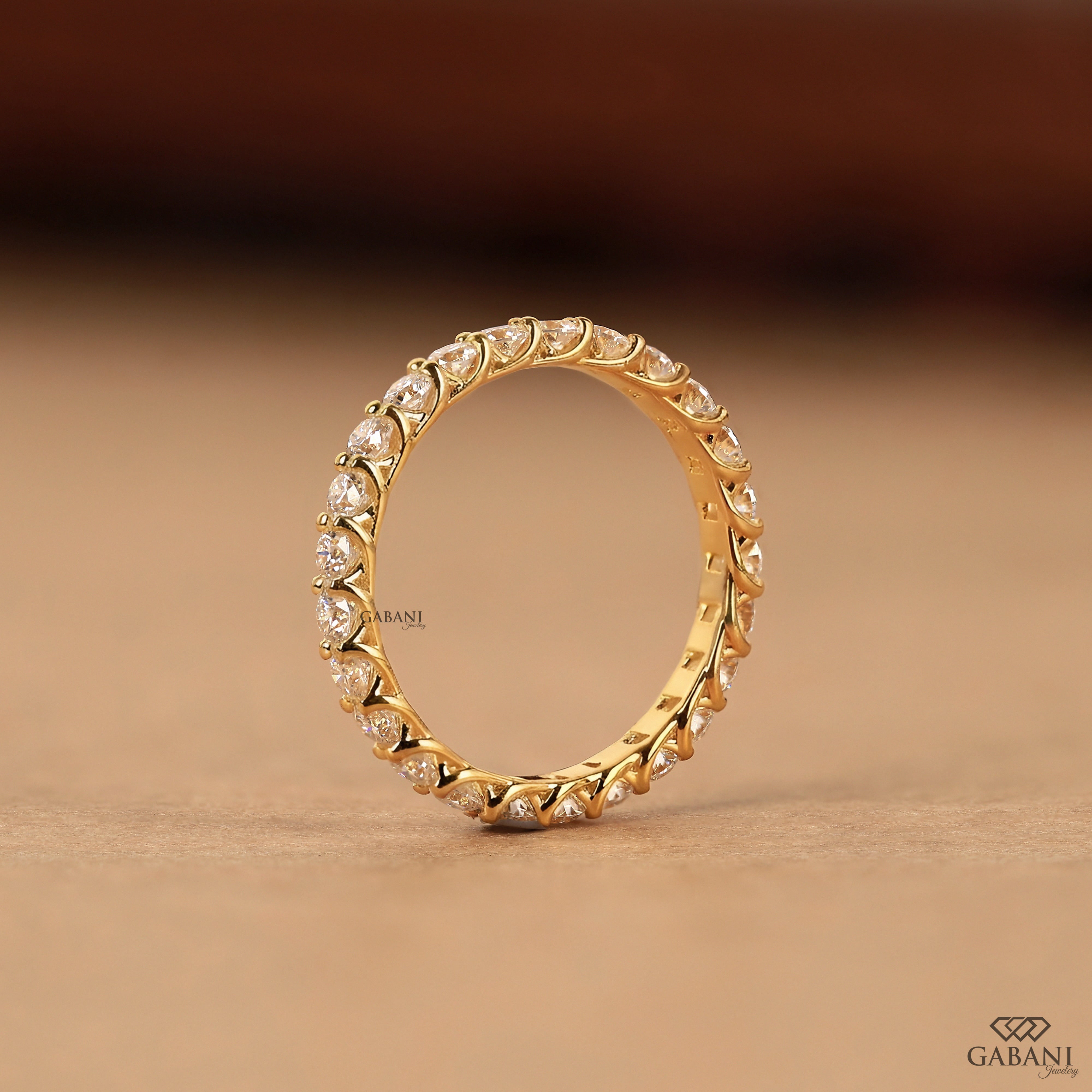 a round lab grown diamond full eternity band in 14K yellow gold, featuring sparkling shared prong set diamonds in a classic wedding band design by Gabani Jewelry.