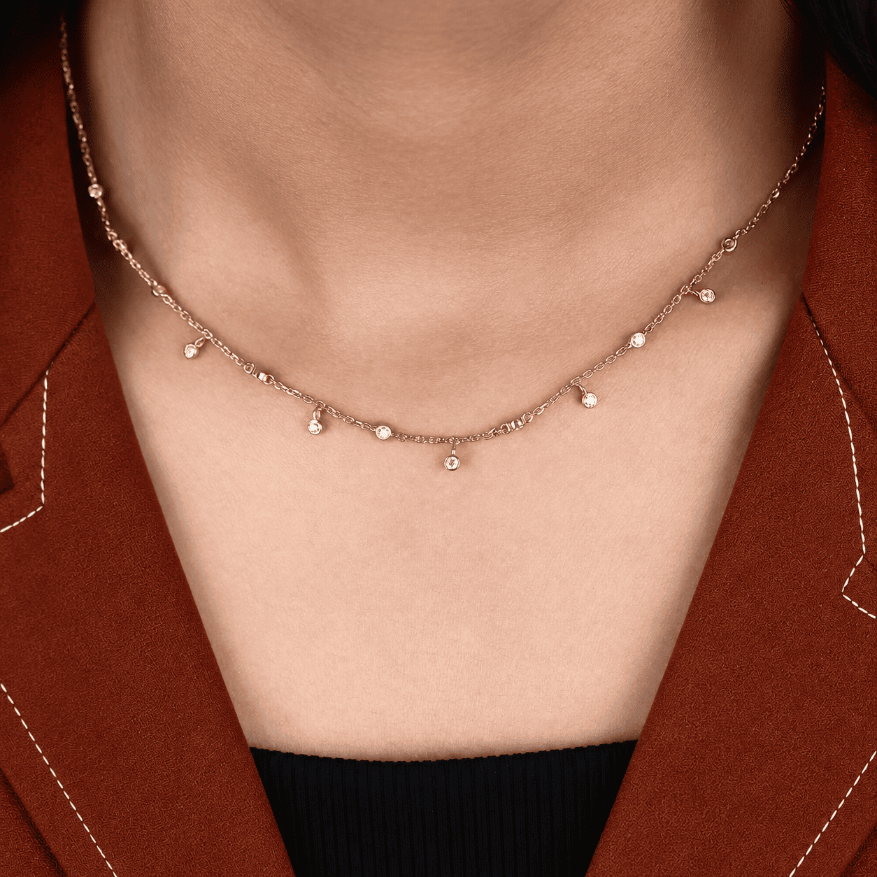 Round cut lab grown diamond station necklace with equal size bezel set diamonds and dangling diamond charms in 18K yellow gold.