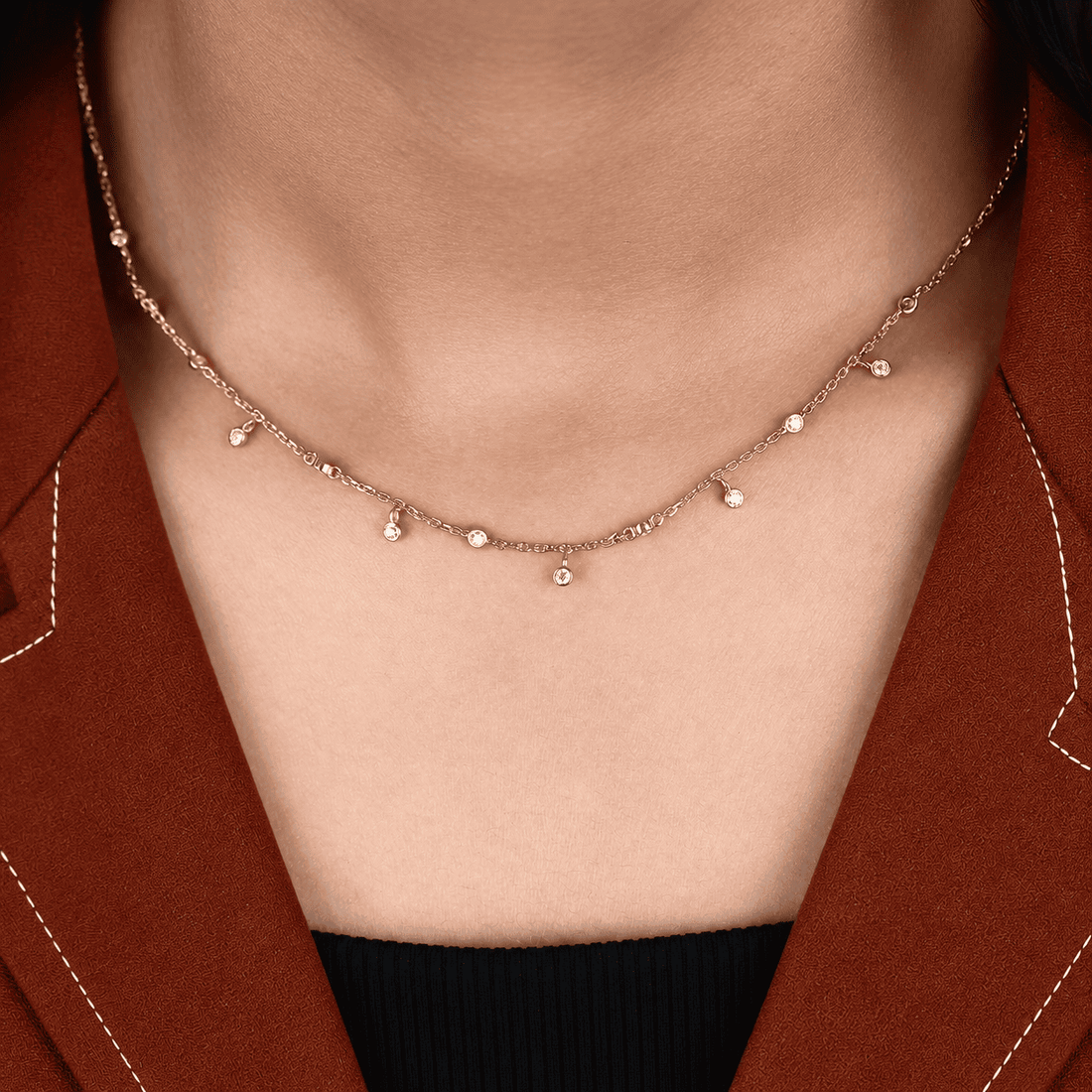 Round cut lab grown diamond station necklace with equal size bezel set diamonds and dangling diamond charms in 18K yellow gold.