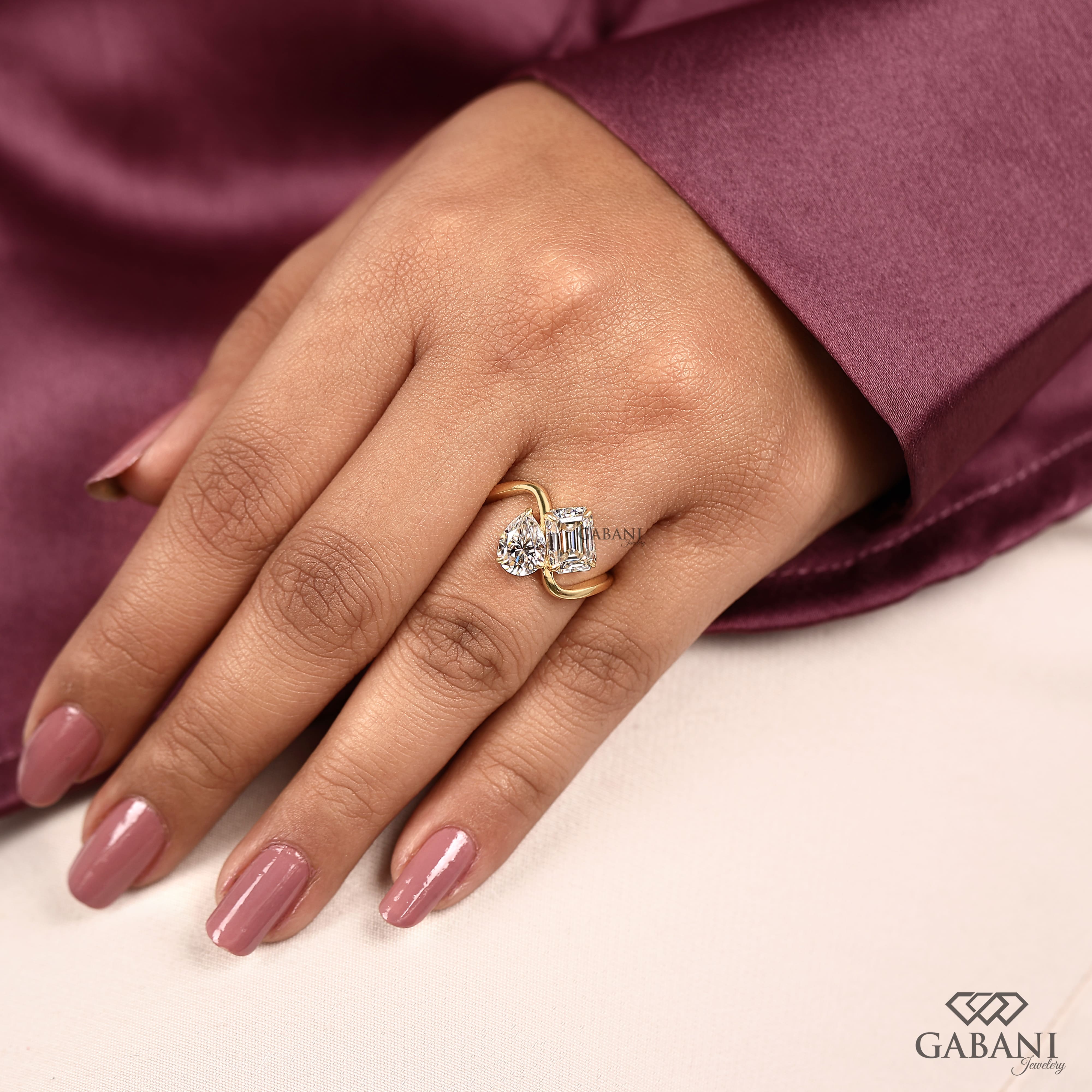 Pear and emerald cut lab grown diamond Toi et Moi ring with a curved yellow gold band, designed for engagement, anniversary, proposal, and statement wear.