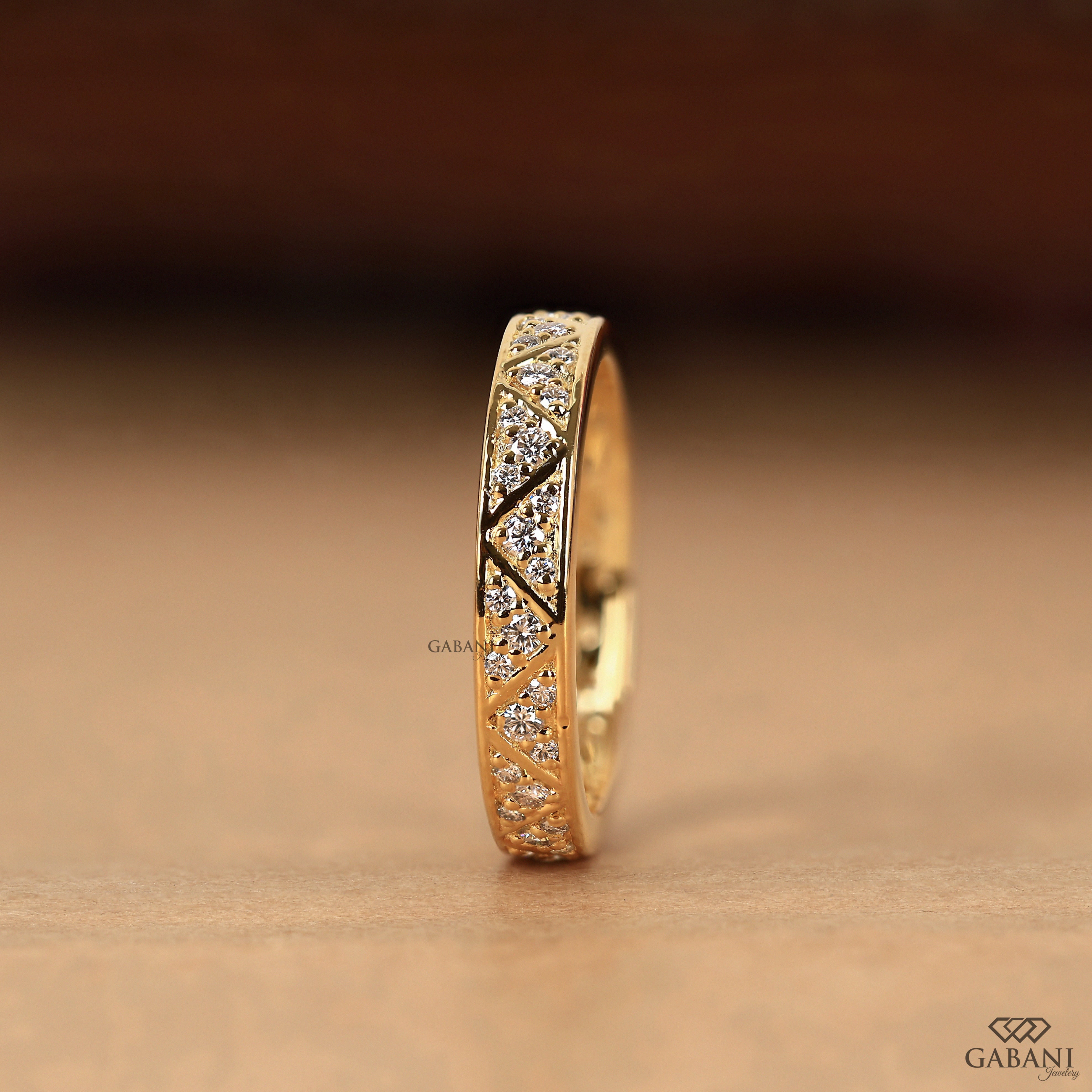 Round lab grown diamond wedding band with geometric triangular pattern and polished yellow gold setting.