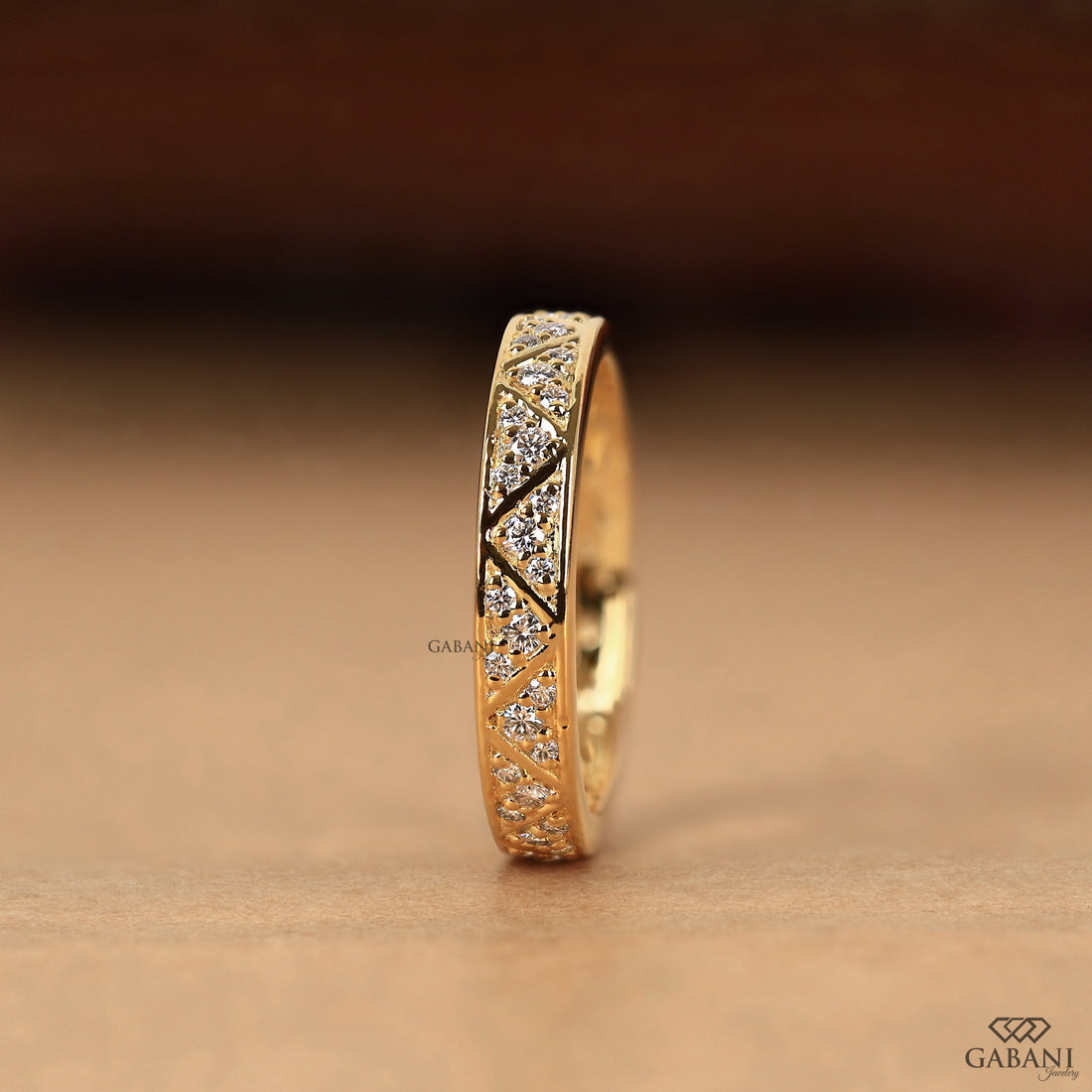 Round lab grown diamond wedding band with geometric triangular pattern and polished yellow gold setting.