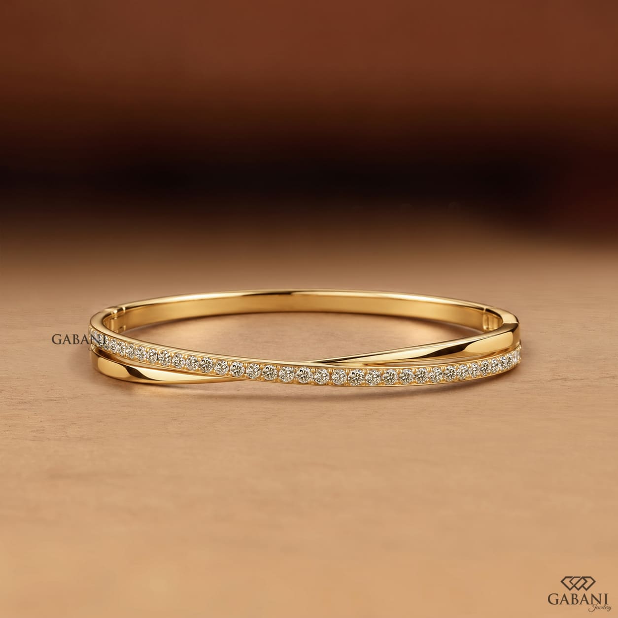 Yellow gold crossover twist bangle bracelet featuring a polished gold band intertwined with a curved row of sparkling round pavé set diamonds.