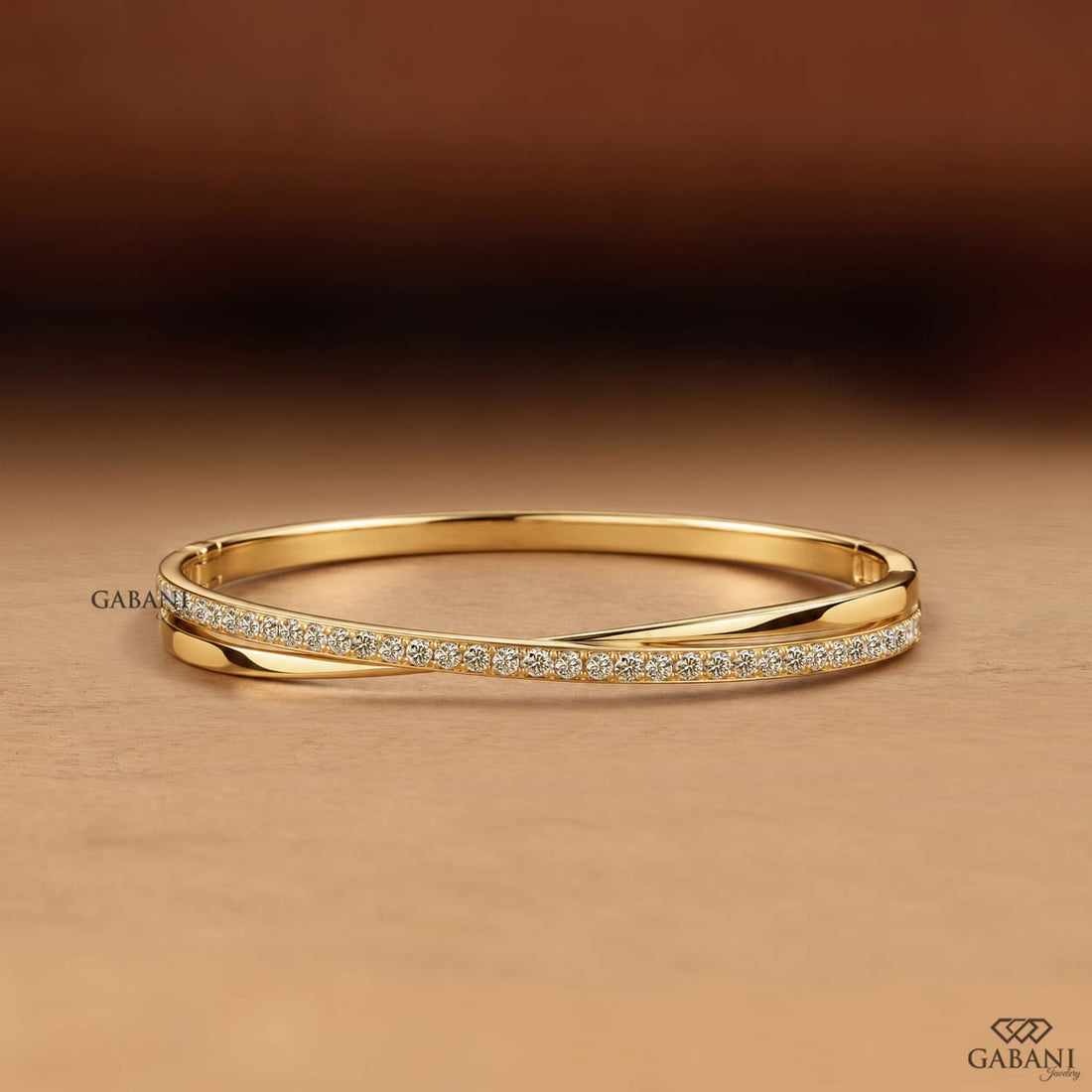 Yellow gold crossover twist bangle bracelet featuring a polished gold band intertwined with a curved row of sparkling round pavé set diamonds.
