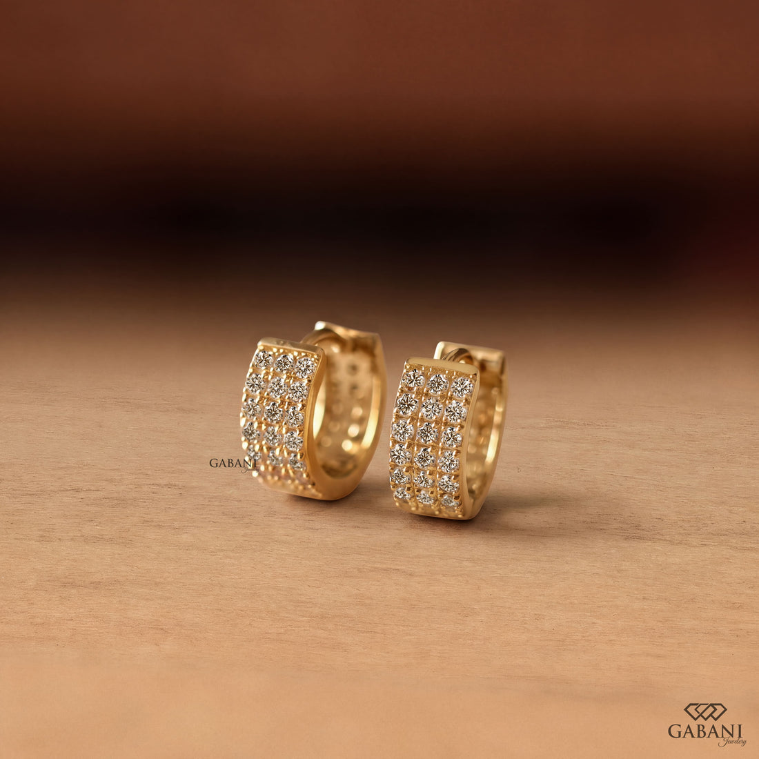 Yellow gold huggie hoop earrings with three rows of round diamonds across the front