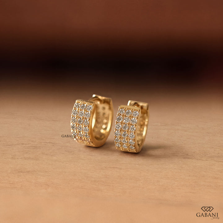 Yellow gold huggie hoop earrings with three rows of round diamonds across the front